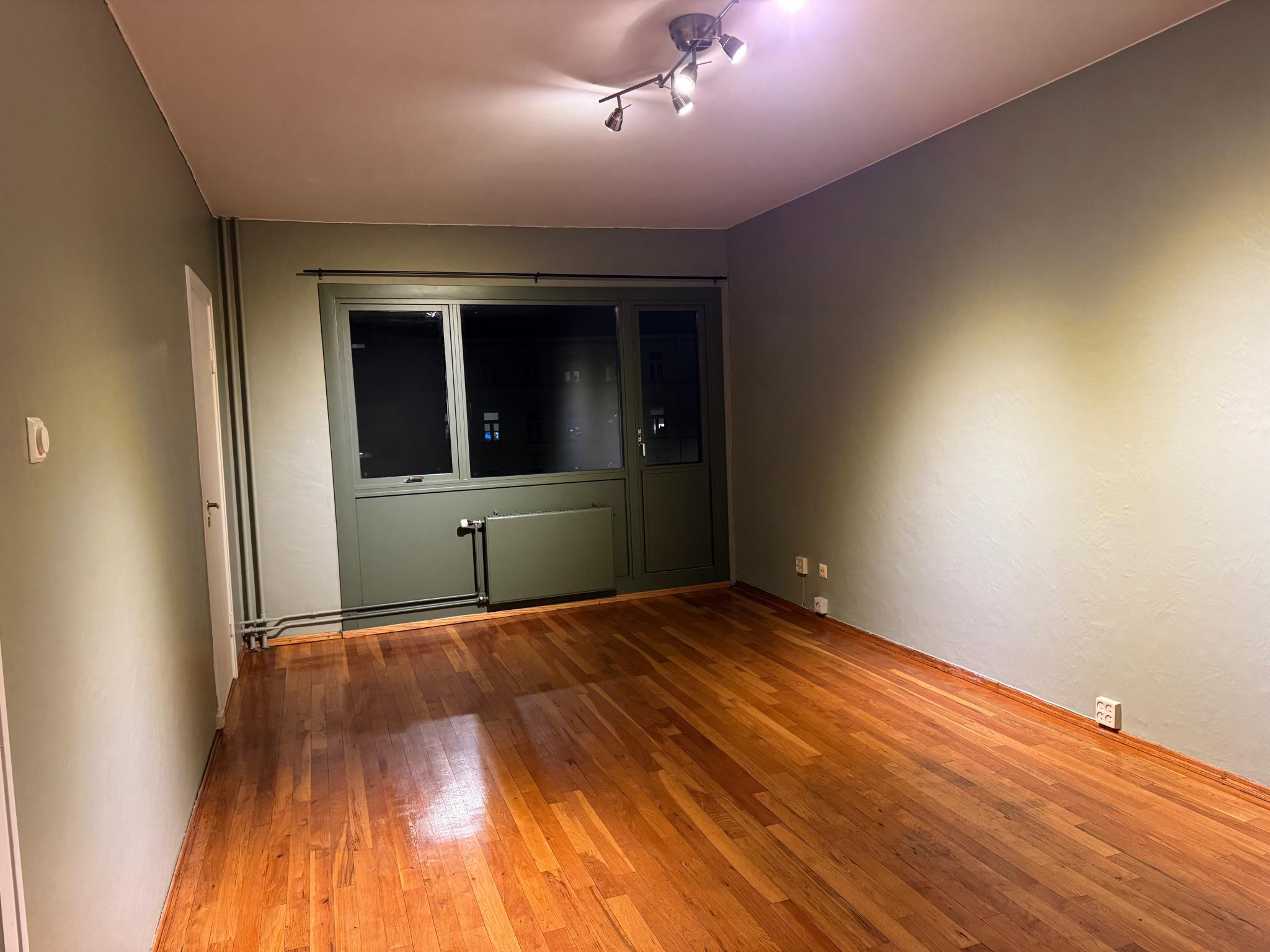 Stue med dør inn til kjøkken og dør inn til gang, samt dør til balkong.