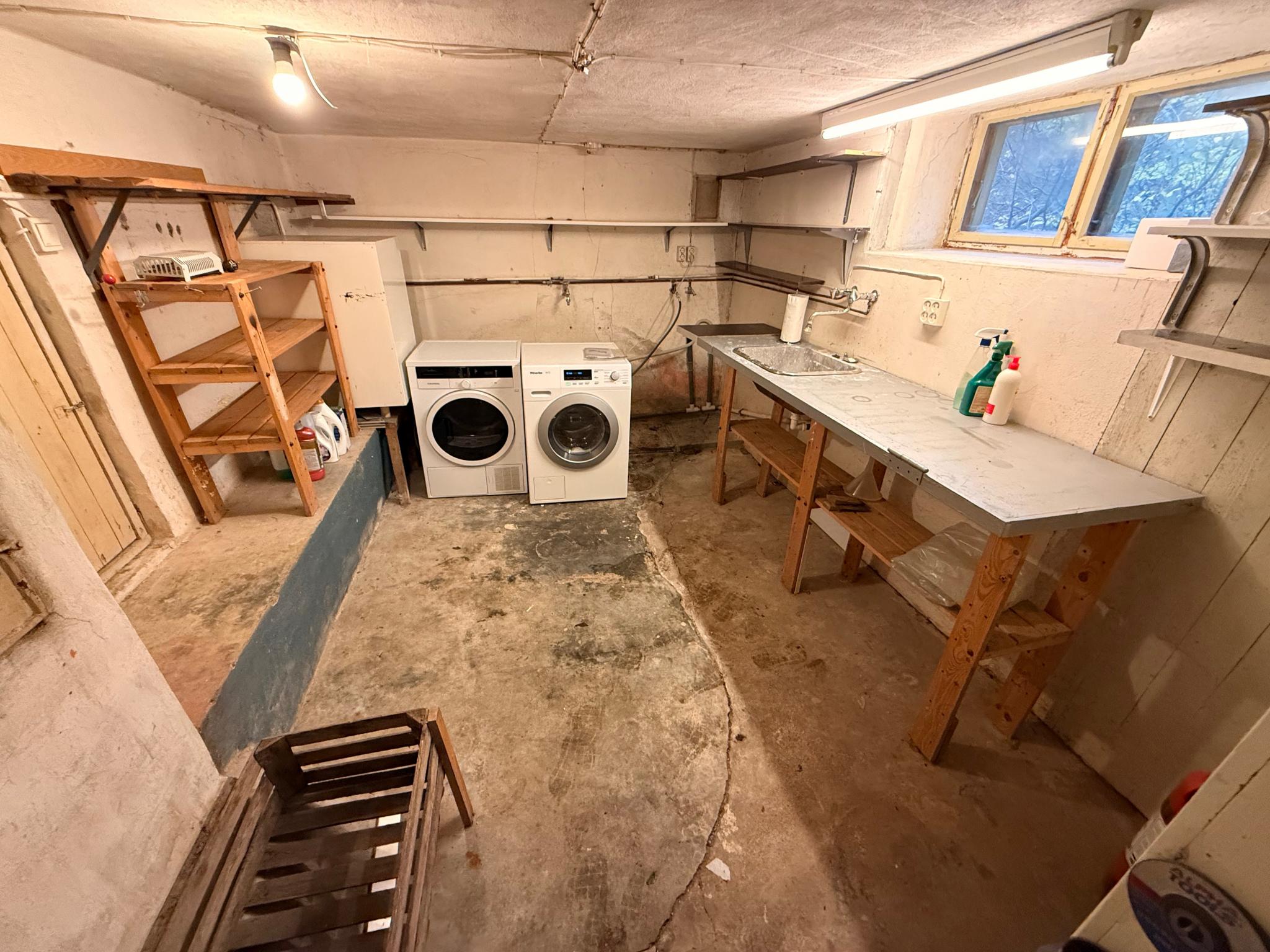 Kjeller med vaskemaskin og tørketrommel og god plass til lagring.