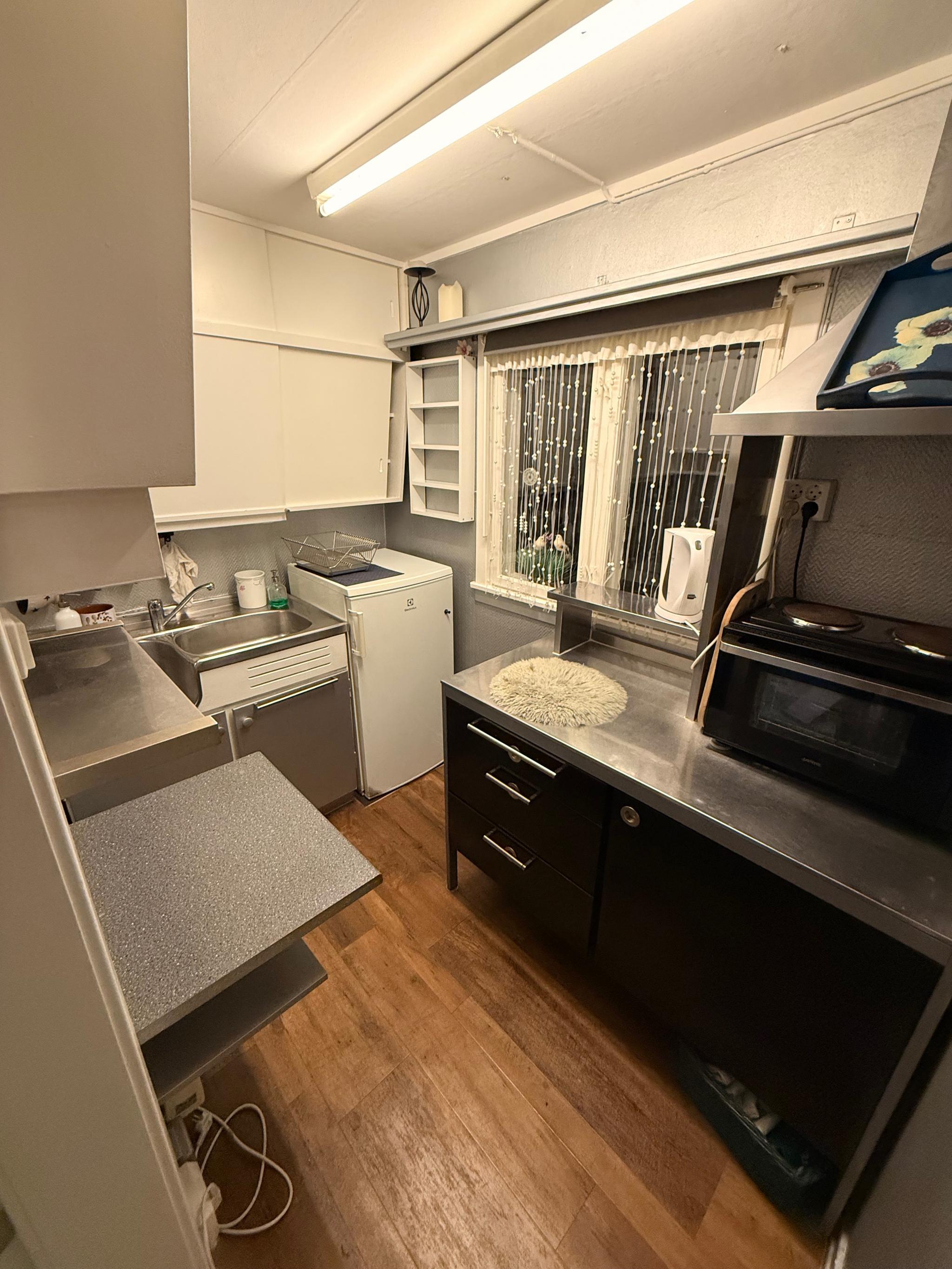 Funksjonelt kjøkken med god benkeplass, mini-komfyr og vask i rustfritt stål. Delvis møblert og klart til bruk.