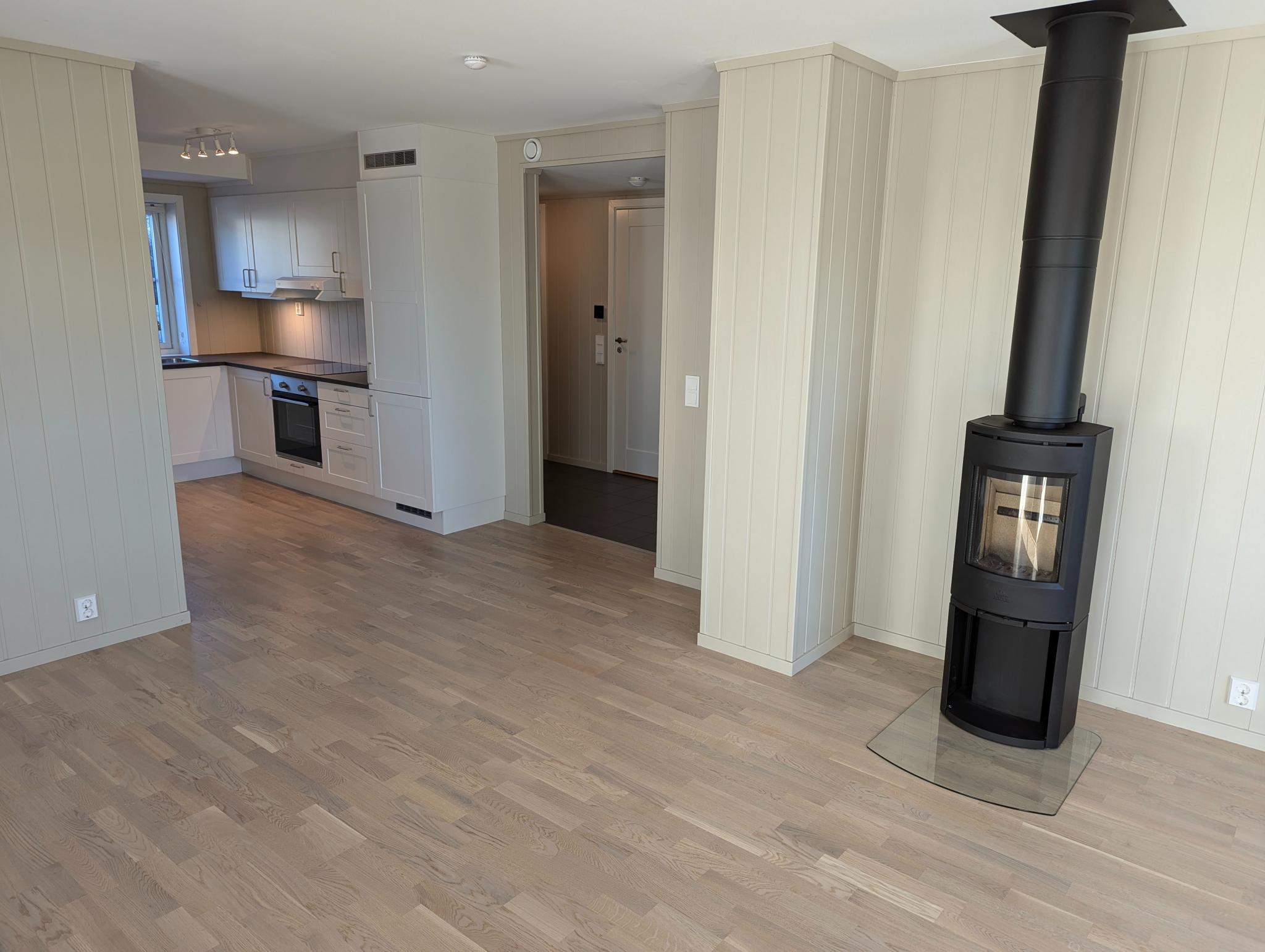 Åpen kjøkkenløsning. Kjøkkeninnredning med hvite, profilerte fronter og mørk laminat benkeplate.