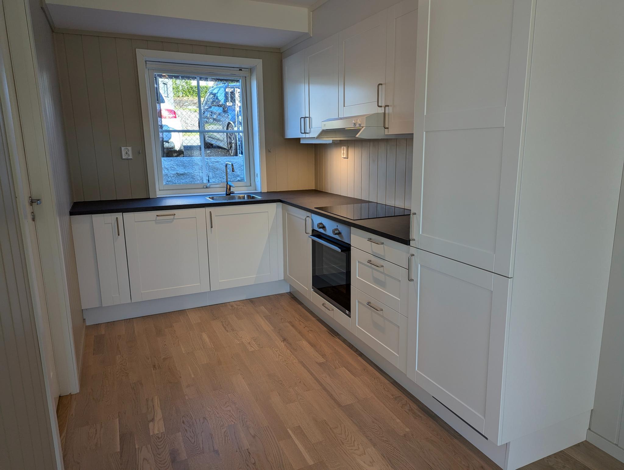 Kjøkkenet er plasseffektivt utformet og har integrerte hvitevarer: Koketopp, komfyr, oppvaskmaskin og kombinert kjøle- og fryseskap