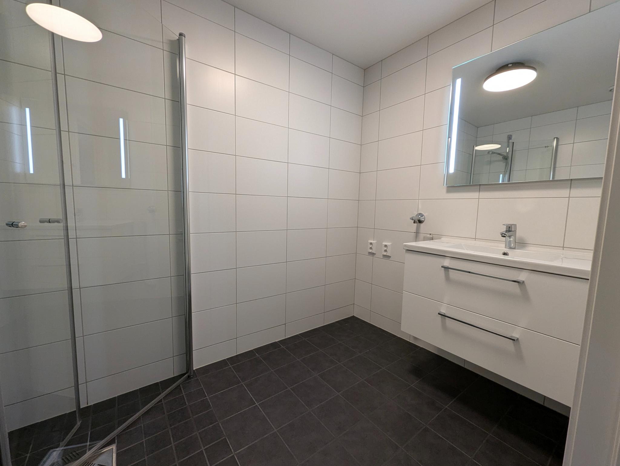 Flislagt bad med gulvvarme, baderomsinnredning og opplegg for vaskemaskin