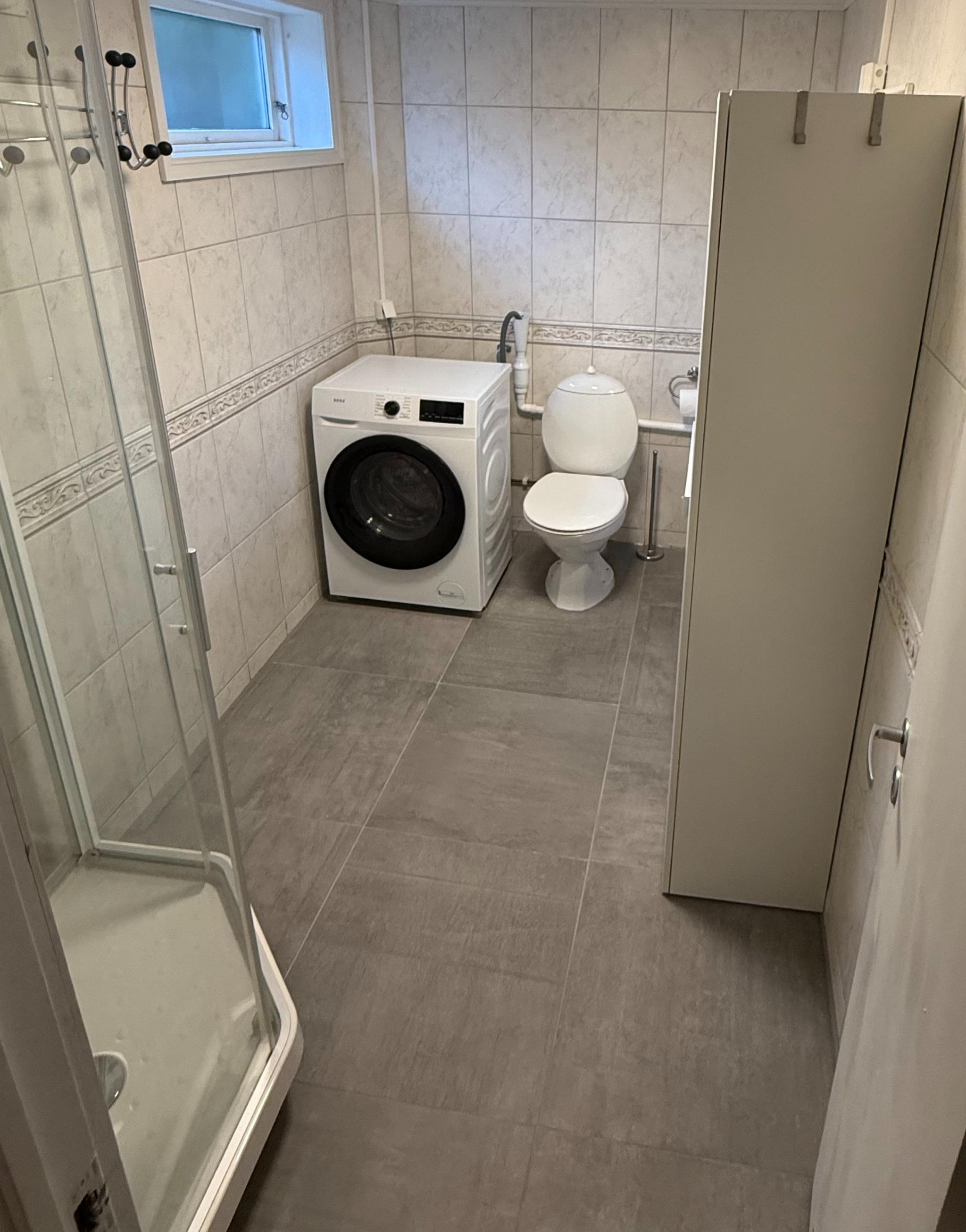 Badet har dusjkabinett og ny kombinert vaskemaskin og tørketrommel.