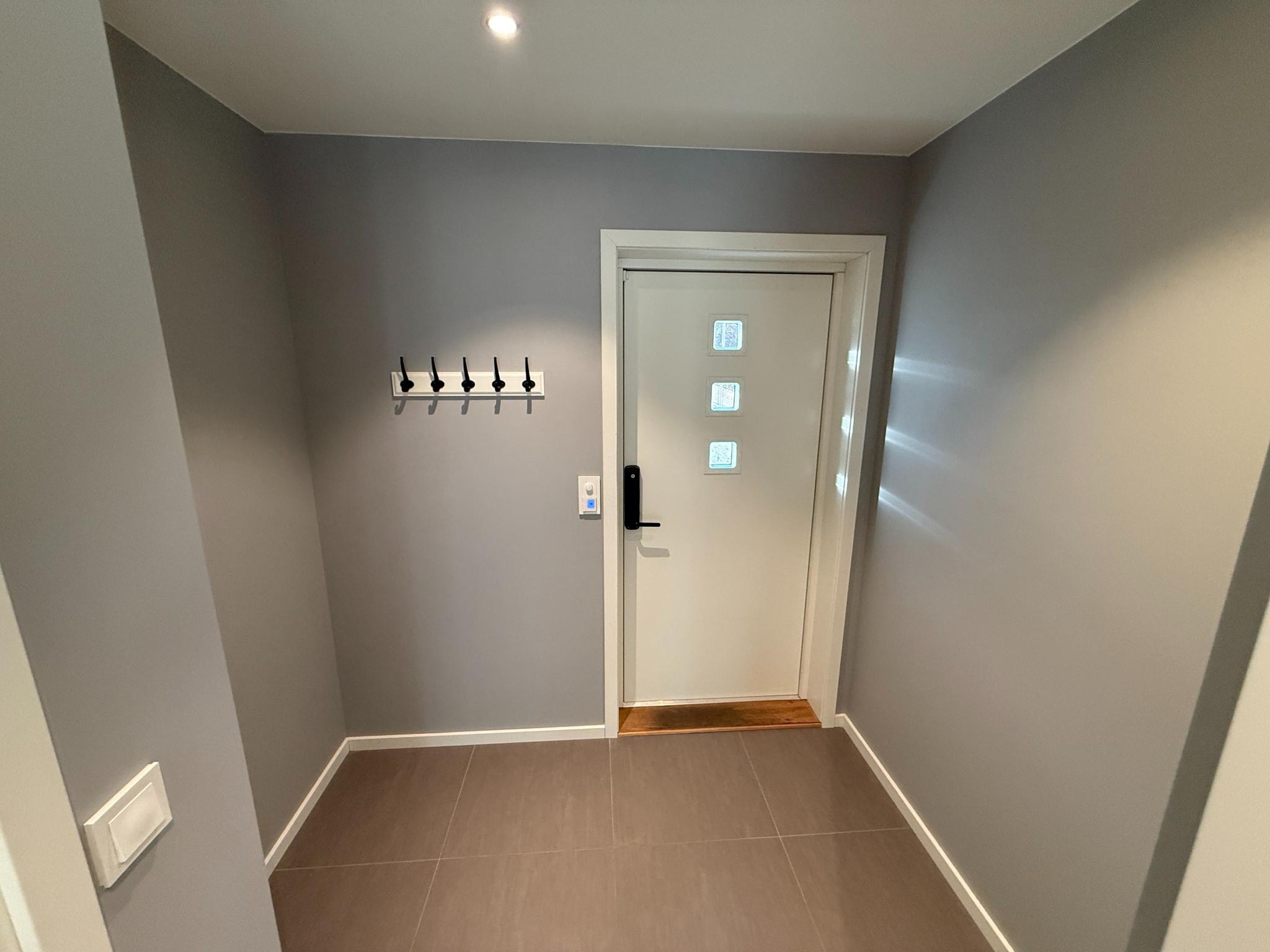 Lys og moderne entré med flislagt gulv, god plass til skohylle og knagger. Privat inngangsdør med vinduer som slipper inn dagslys.