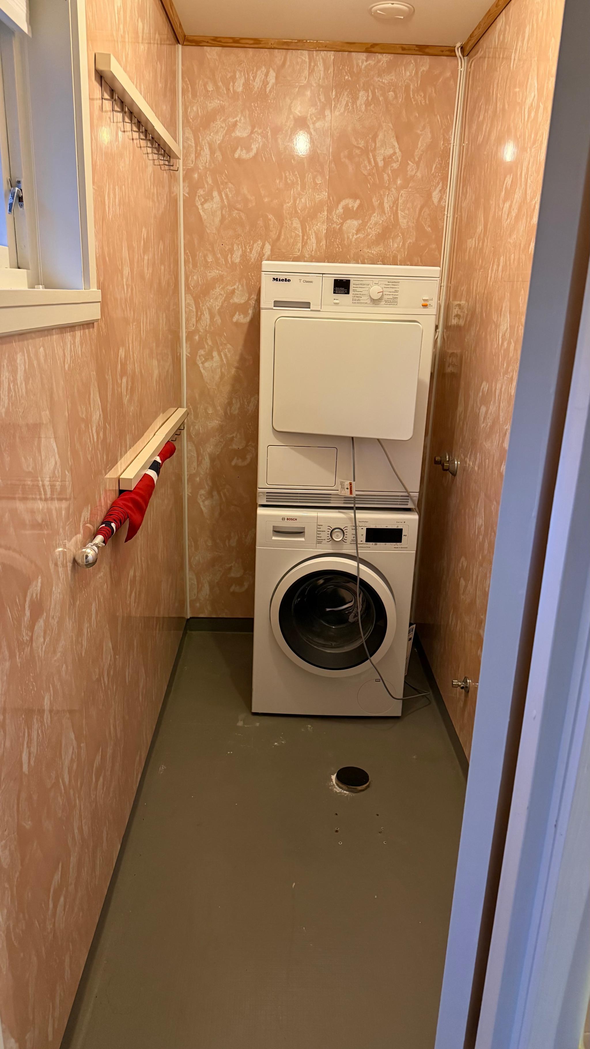 Lite vaskerom med vaskemaskin/tørketrommel og tørkestativ. 
