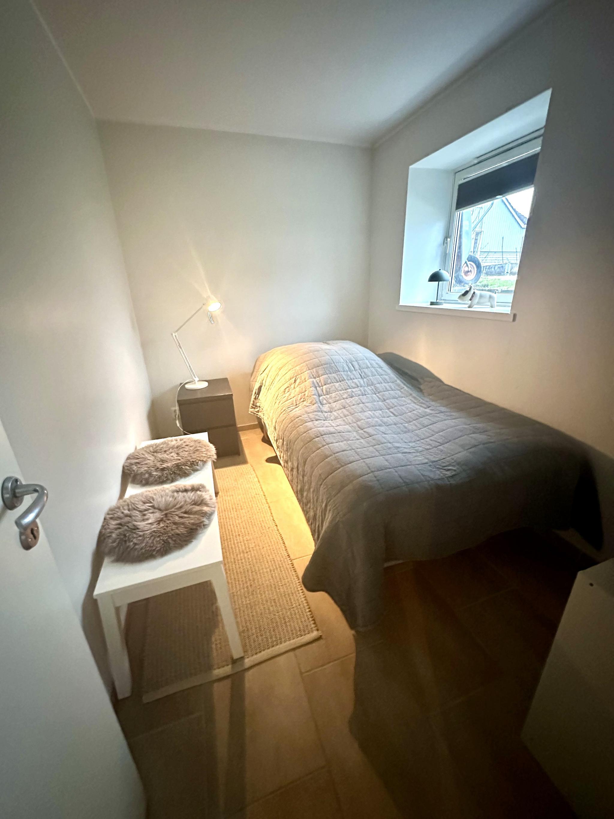 Det ene soverommet med vindu ut mot hagen på baksiden av boligen. Bildet er tatt fra inngangen til rommet. 