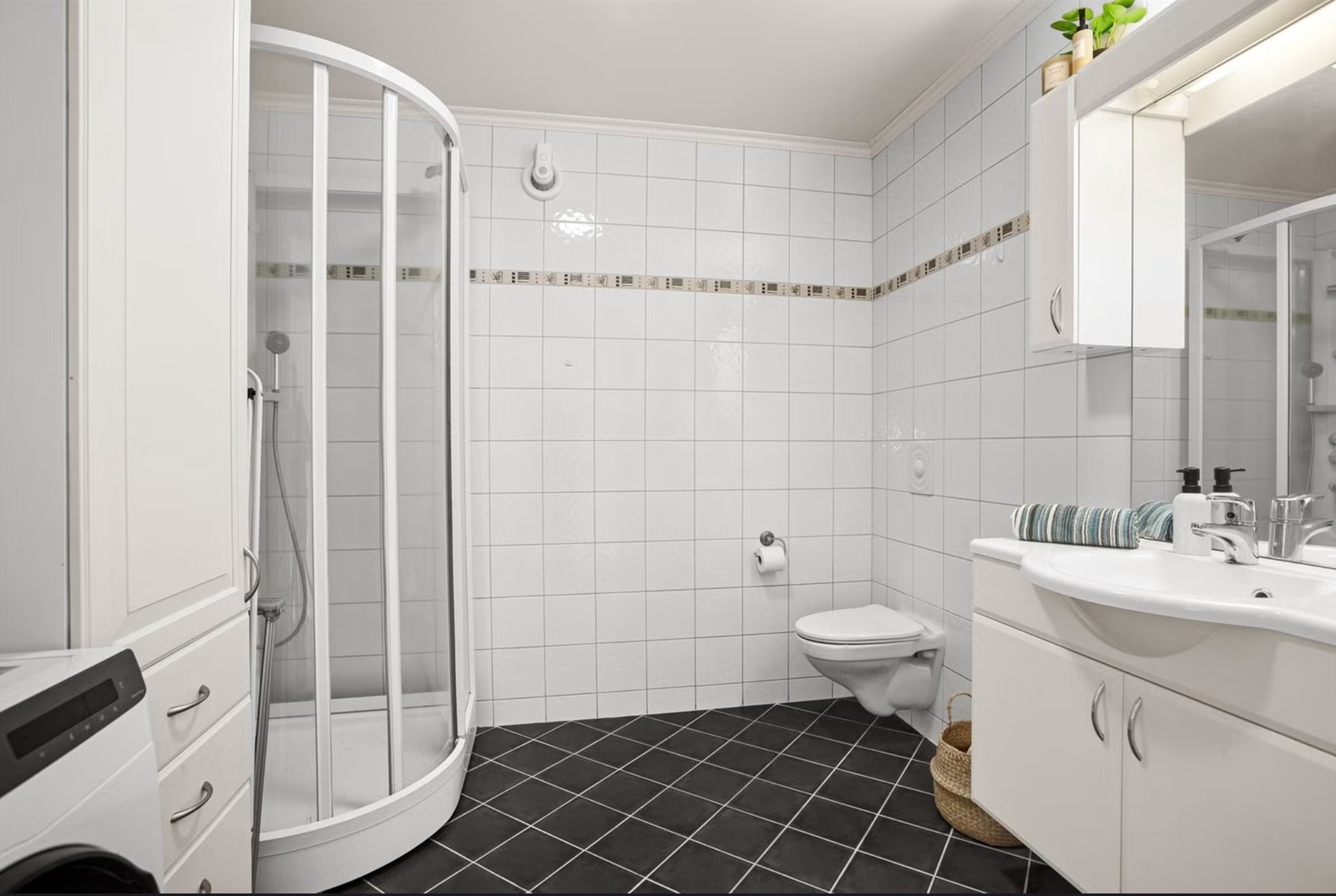 Bad med toalett, dusj og opplegg for vaskemaskin.