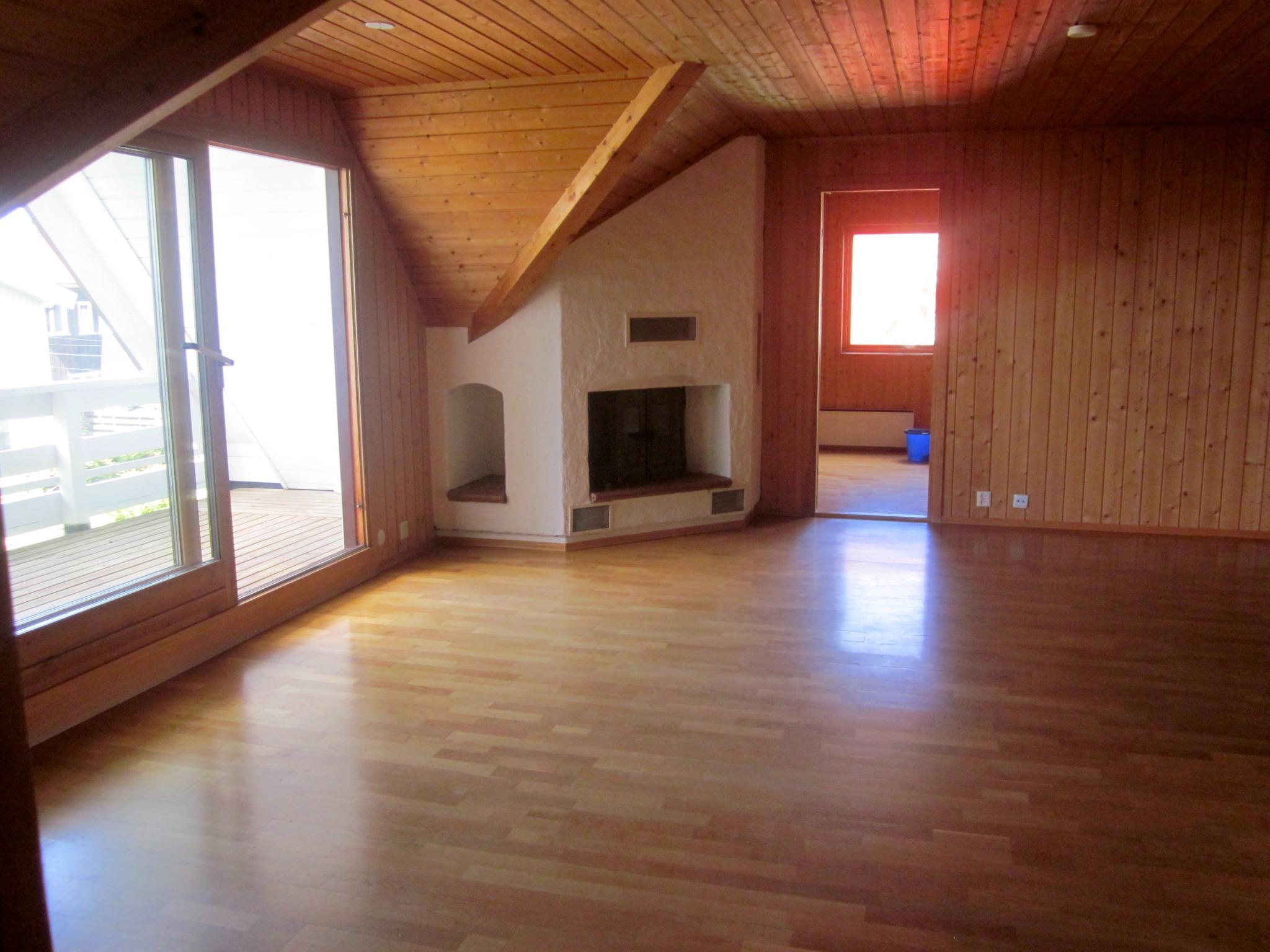 Stor stue med peis og utgang ballkong. Inngang til kjøkken ved siden av peisen.