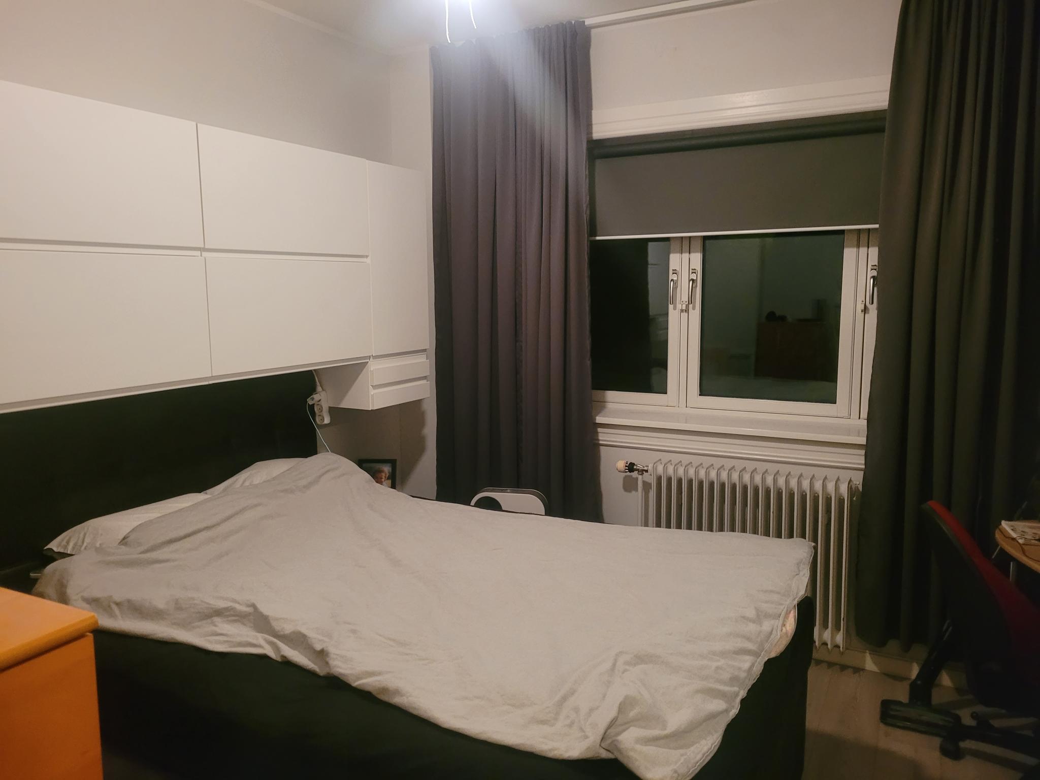 Rullegardin og lystette gardiner som går fra tak til gulv, så det er mørkt på soverommet selv med sola rett imot.