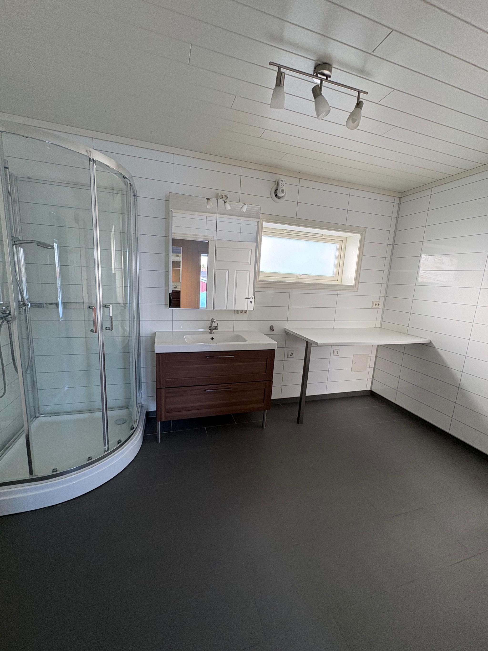 Bad med toalett, dusj, servant, bord og skap