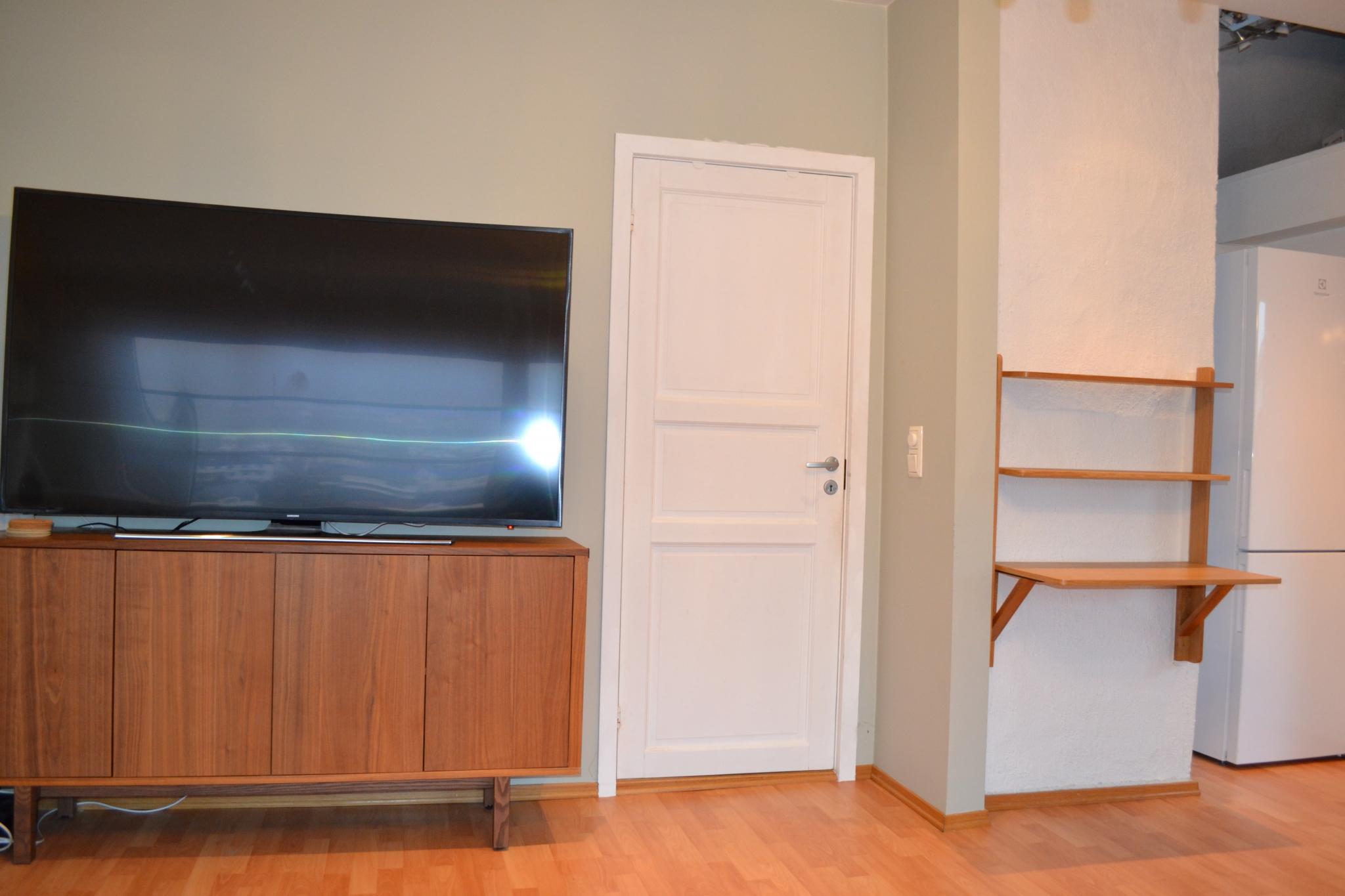 Stort TV med romslig skjenk.
Inngang til soverom.