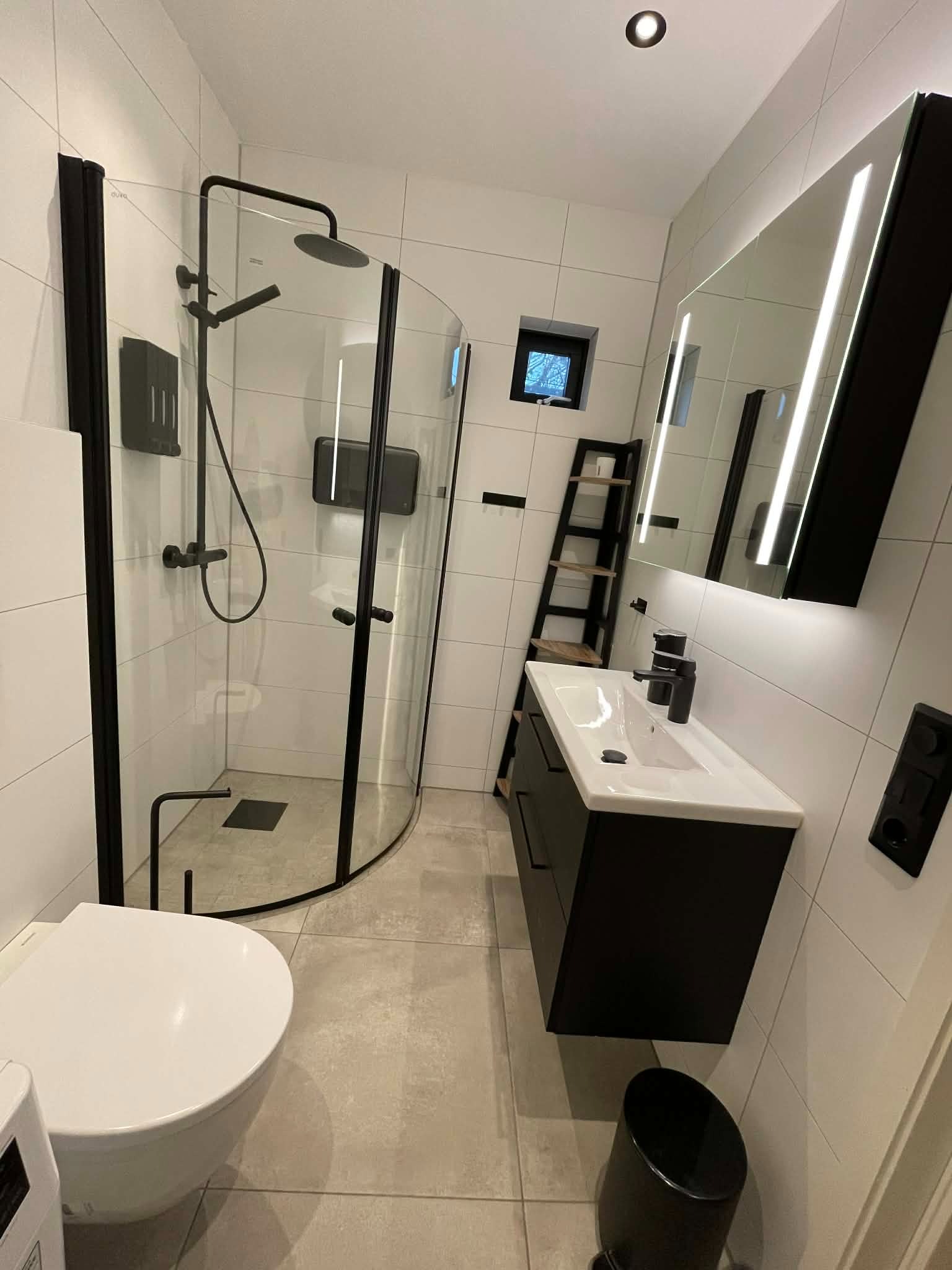 Moderne fullfliset bad med speilskap og varmekabler.