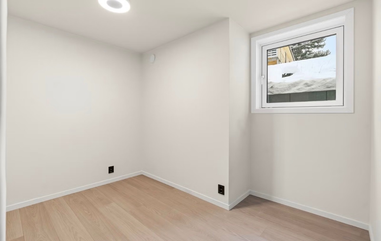 Lyst soverom med vindu, panelovn og god gulvplass.