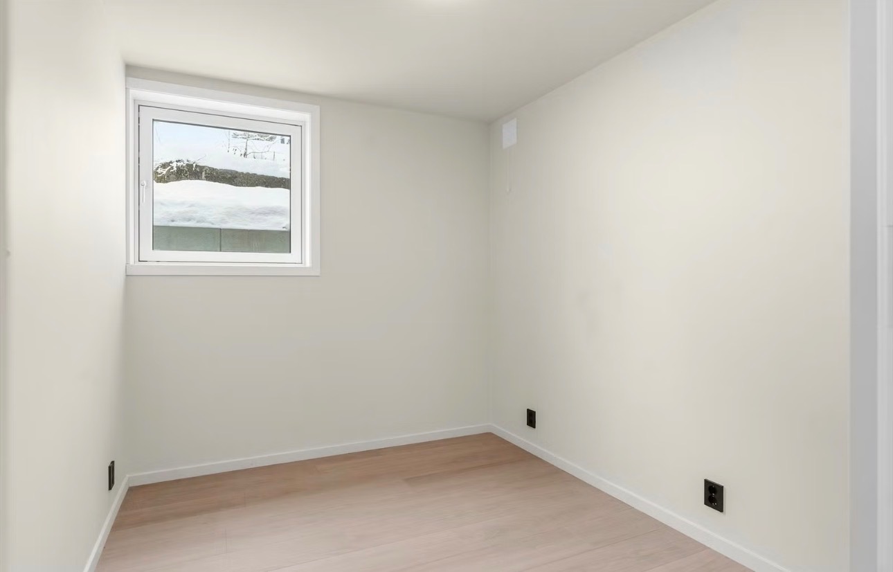 Lyst soverom med vindu og panelovn - plass til seng, nattbord og garderobeløsning.