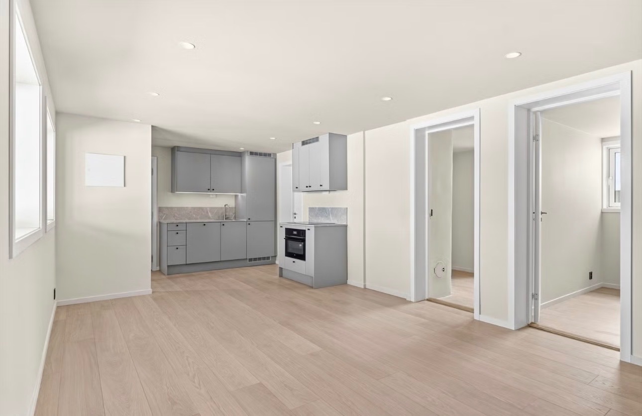 Romslig stue i åpen løsning mot fullt utstyrt kjøkken med Aubo-innredning fra 2025.