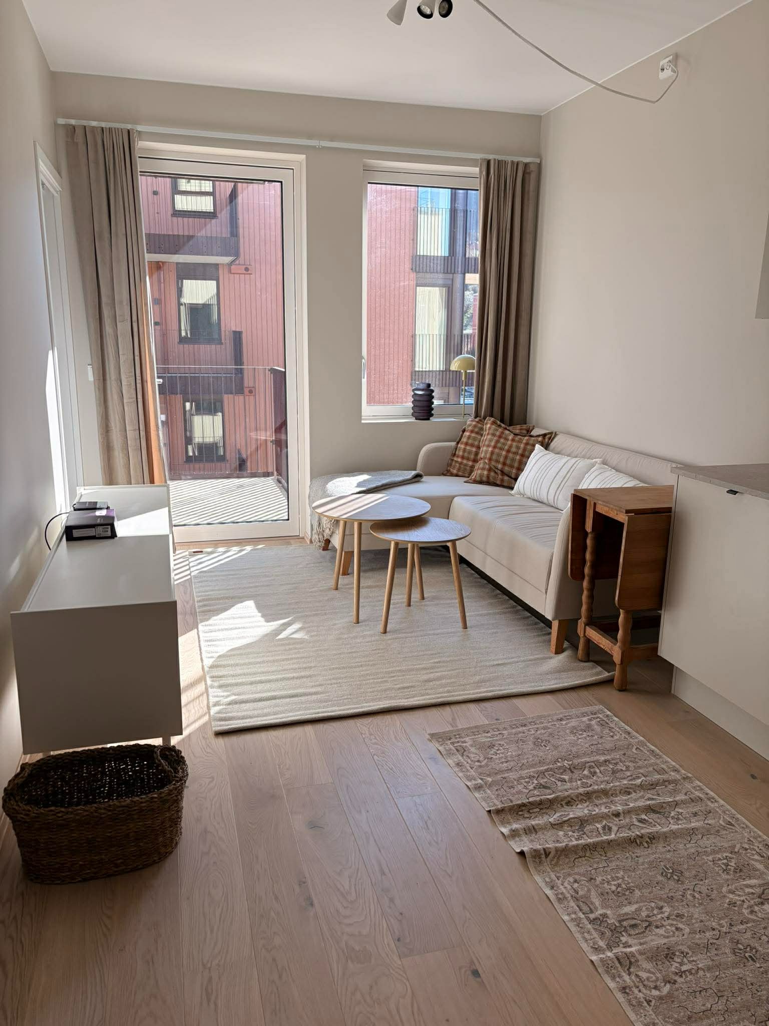 Stuen er møblert med sofa, sofabord, gardiner, TV-benk, spisebord og to stoler