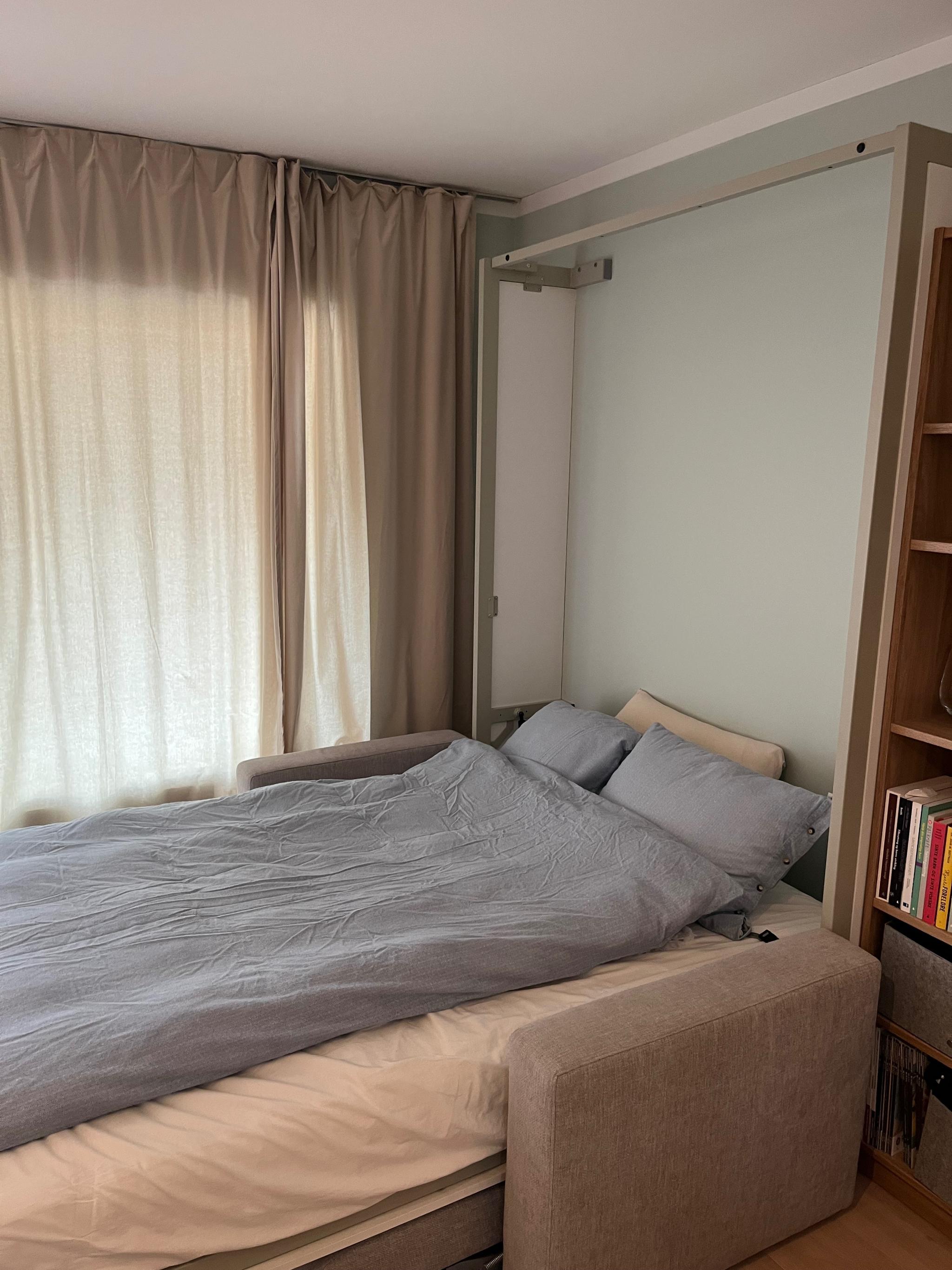 Sofaen «forsvinner» under sengen når den felles ned. Sengen er 150 cm bred. Sengetøy og dyne/pute får plass inni når sengen felles opp.
