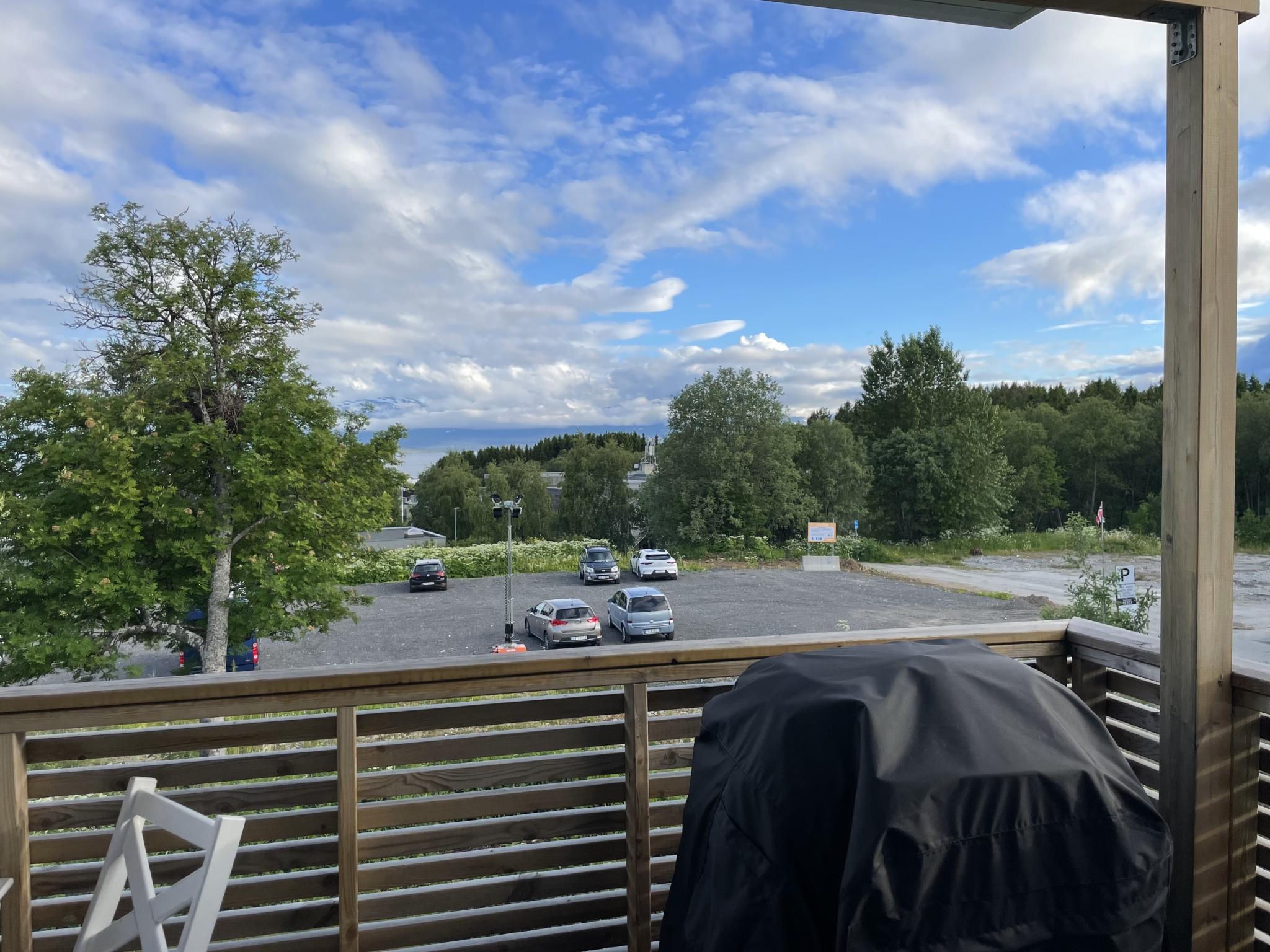 Utsikt fra balkong. Parkeringsplassen er lite brukt. Gangsti ned til Sørtromsøya sykehjem og Tromsø museum til høyre for parkeringsplassen.