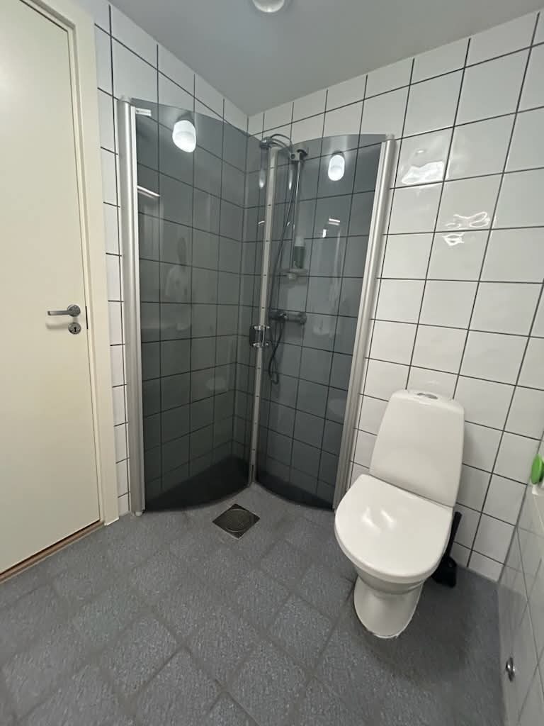 Bad med toalett og dusj. Inngang til oppbevaringsbod og fryser 