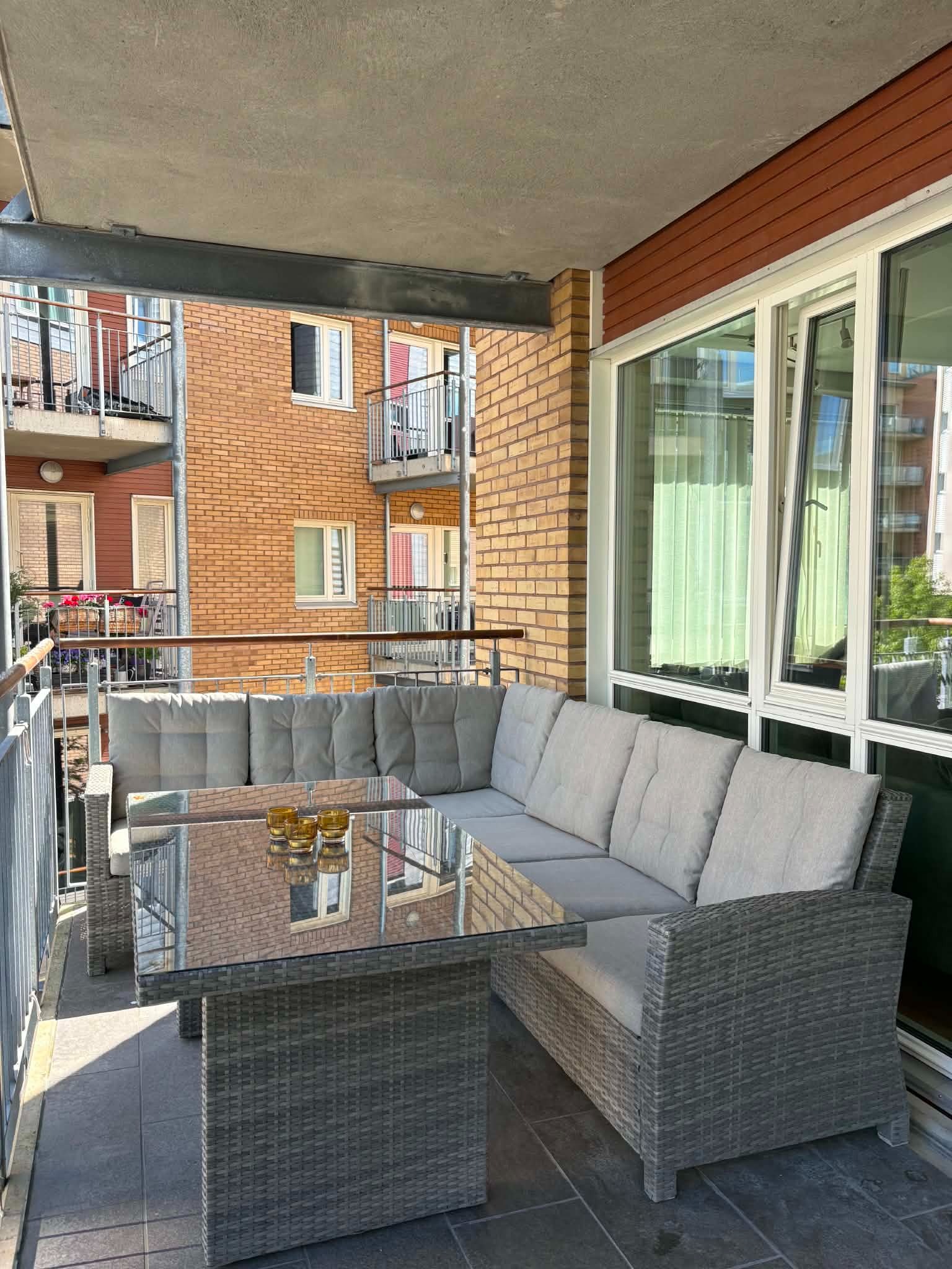Balkong utstyrt med sofagruppe, spisebord og grill