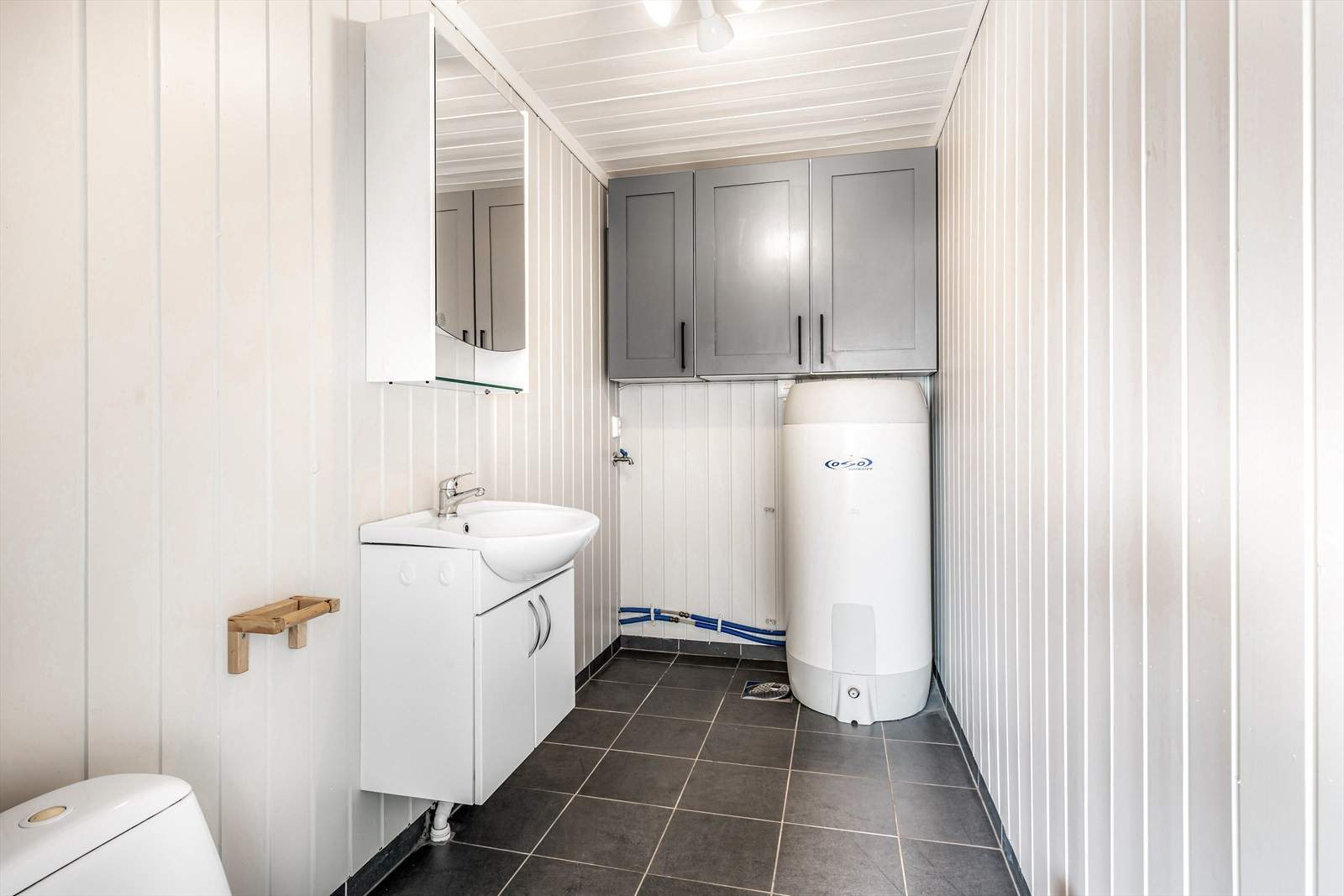 Toalett og vaskerom med opplegg til vaskemaskin. Stor varmtvannsbereder.