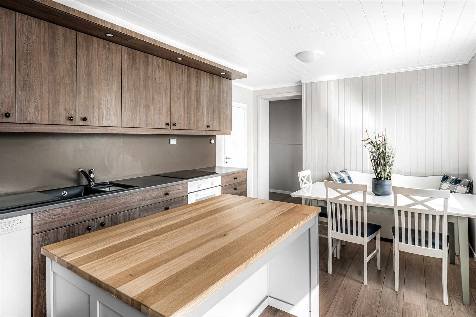 Kjøkken med kjøkkenøy, integrert oppvaskmaskin, platetopp og stekeovn. Ventilator med avtrekk ut.