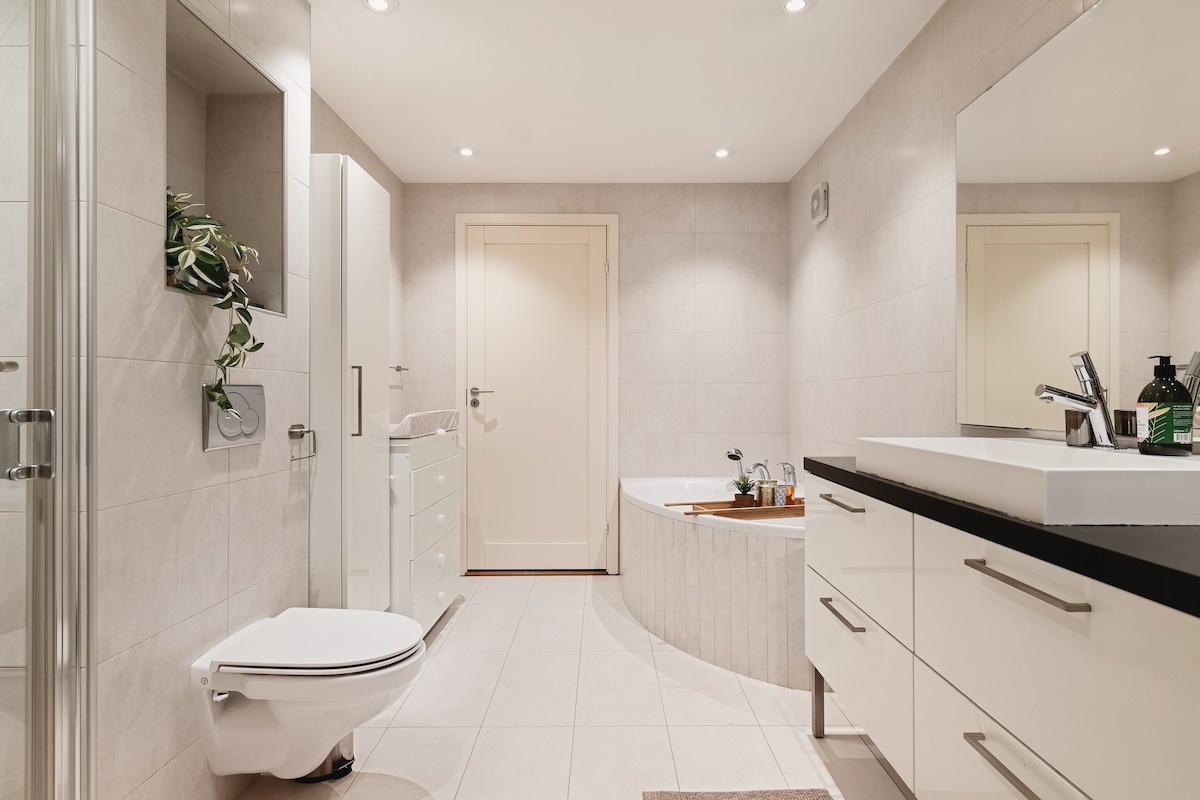 Badet er romslig, flisebelagt med varme i gulvet. Det har et romslig badekar, og god plass til oppbevaring i interiør. 