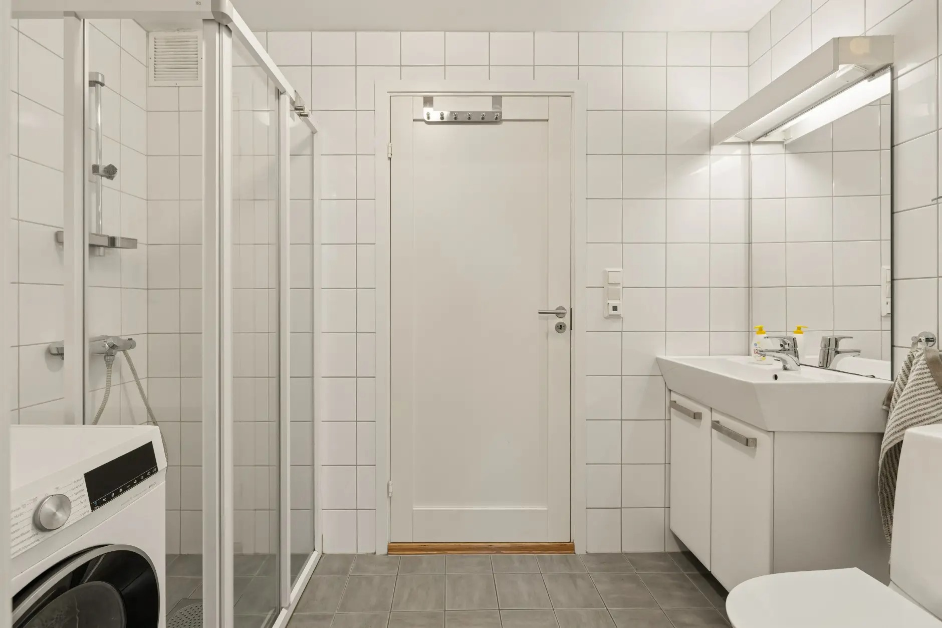 Flislagt bad med varmekabler i gulvet og opplegg for vaskemaskin.