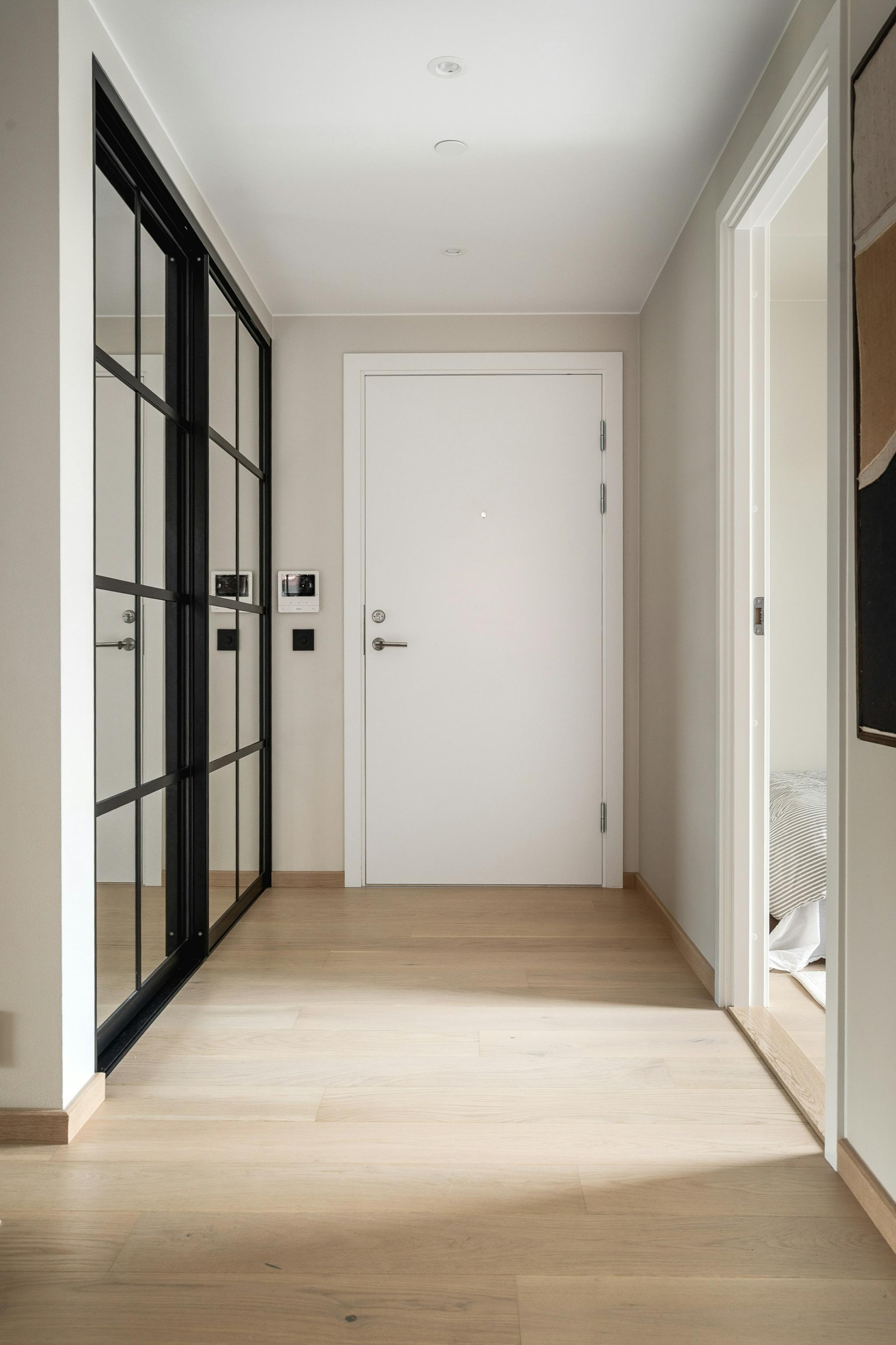 Inngangsperti med skyvegarderobe i jern og innfelte glassfelt