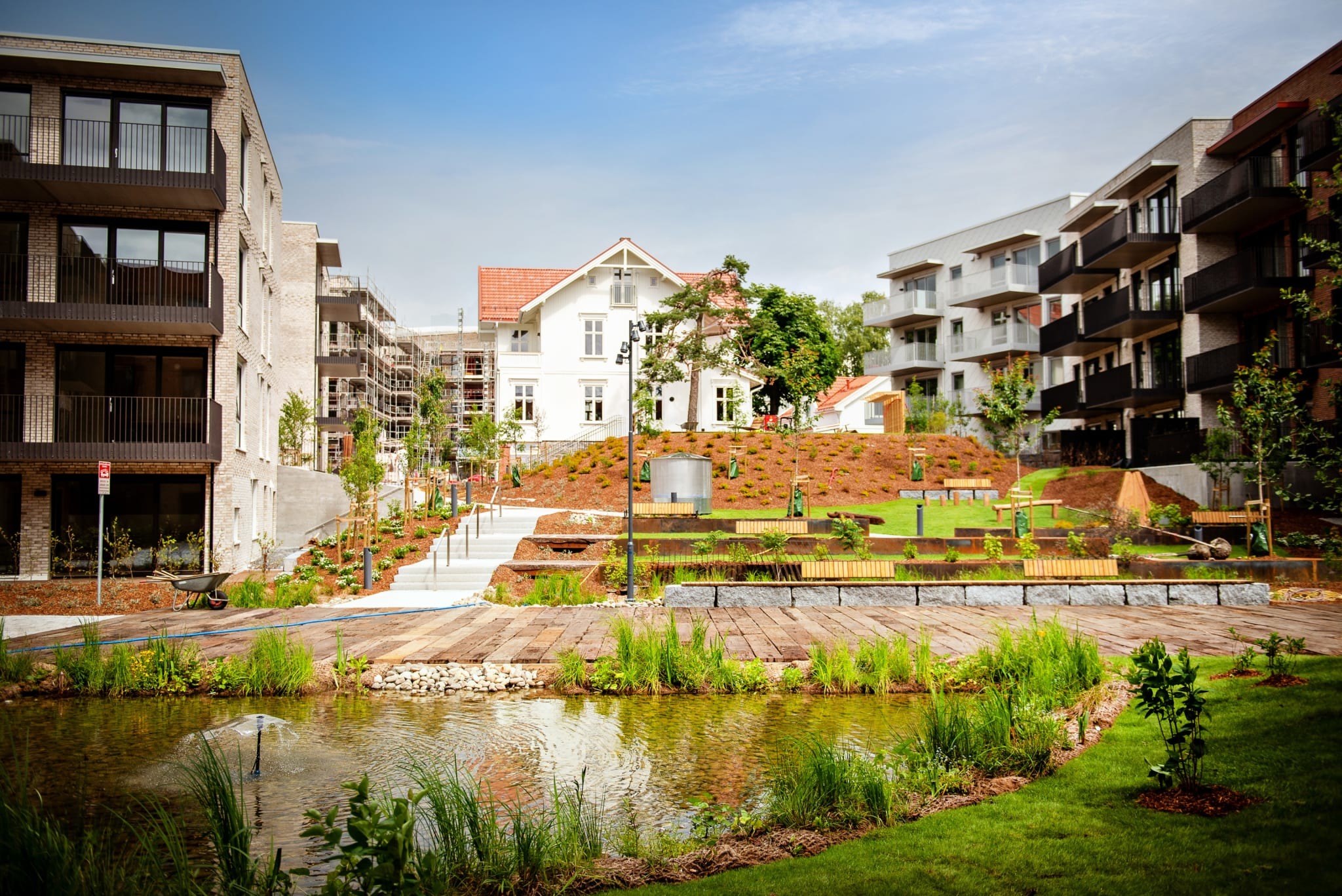 Frodig hage med vannspeil. Leiligheten til høyre i bildet