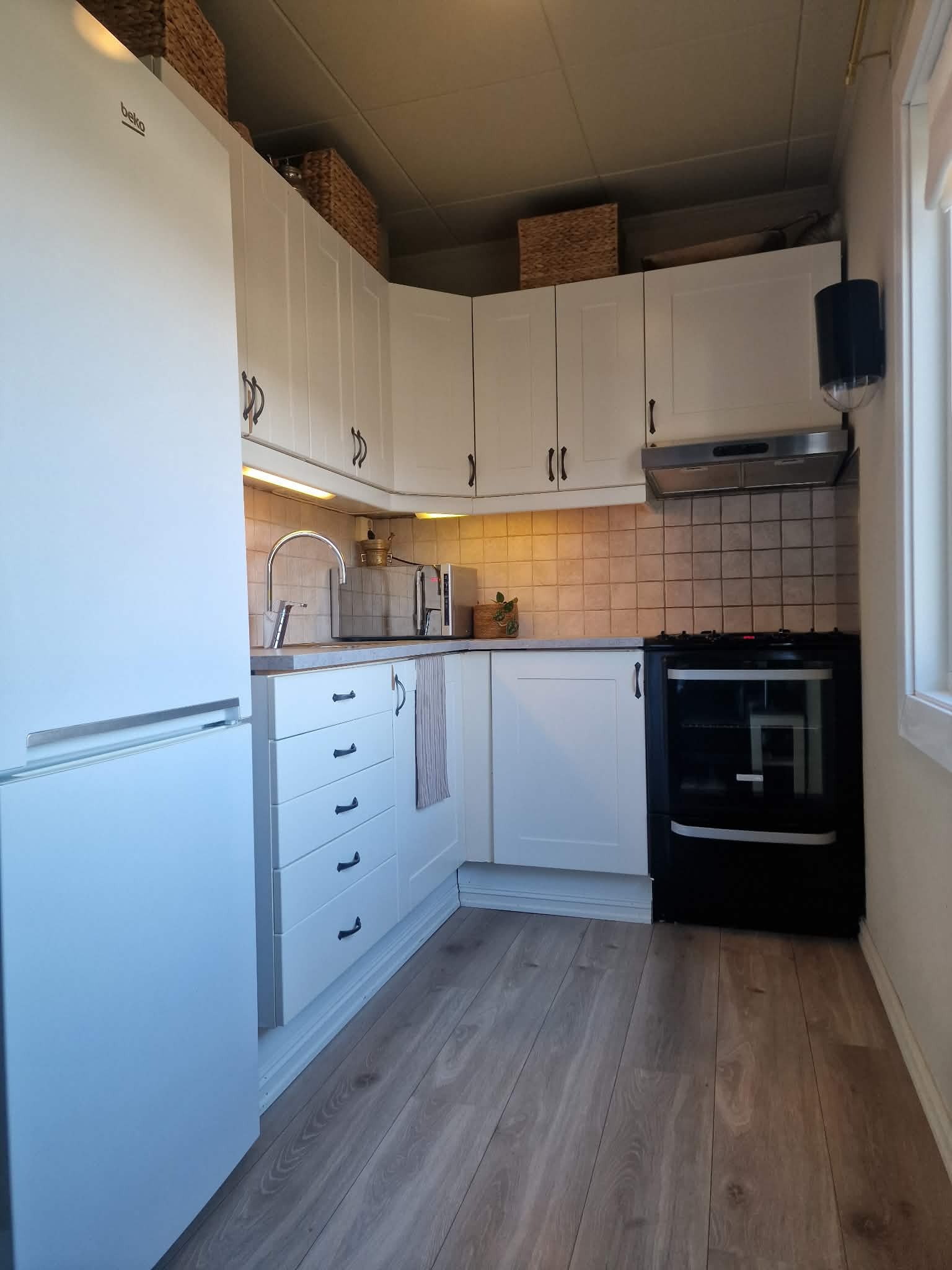 Kjøkken med kjøleskap, mikrobølgeovn og komfyr.