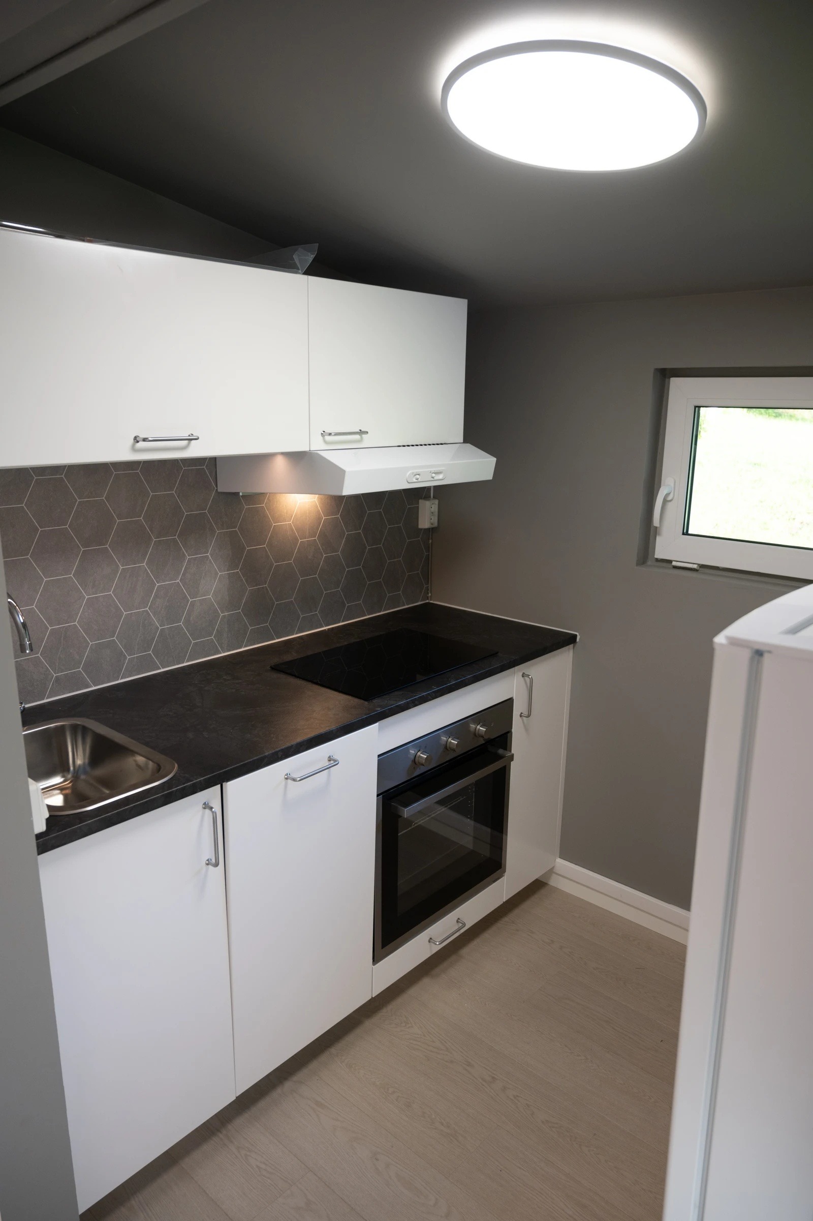 Kjøkken med induksjon, komfyr og integrert oppvaskmaskin.