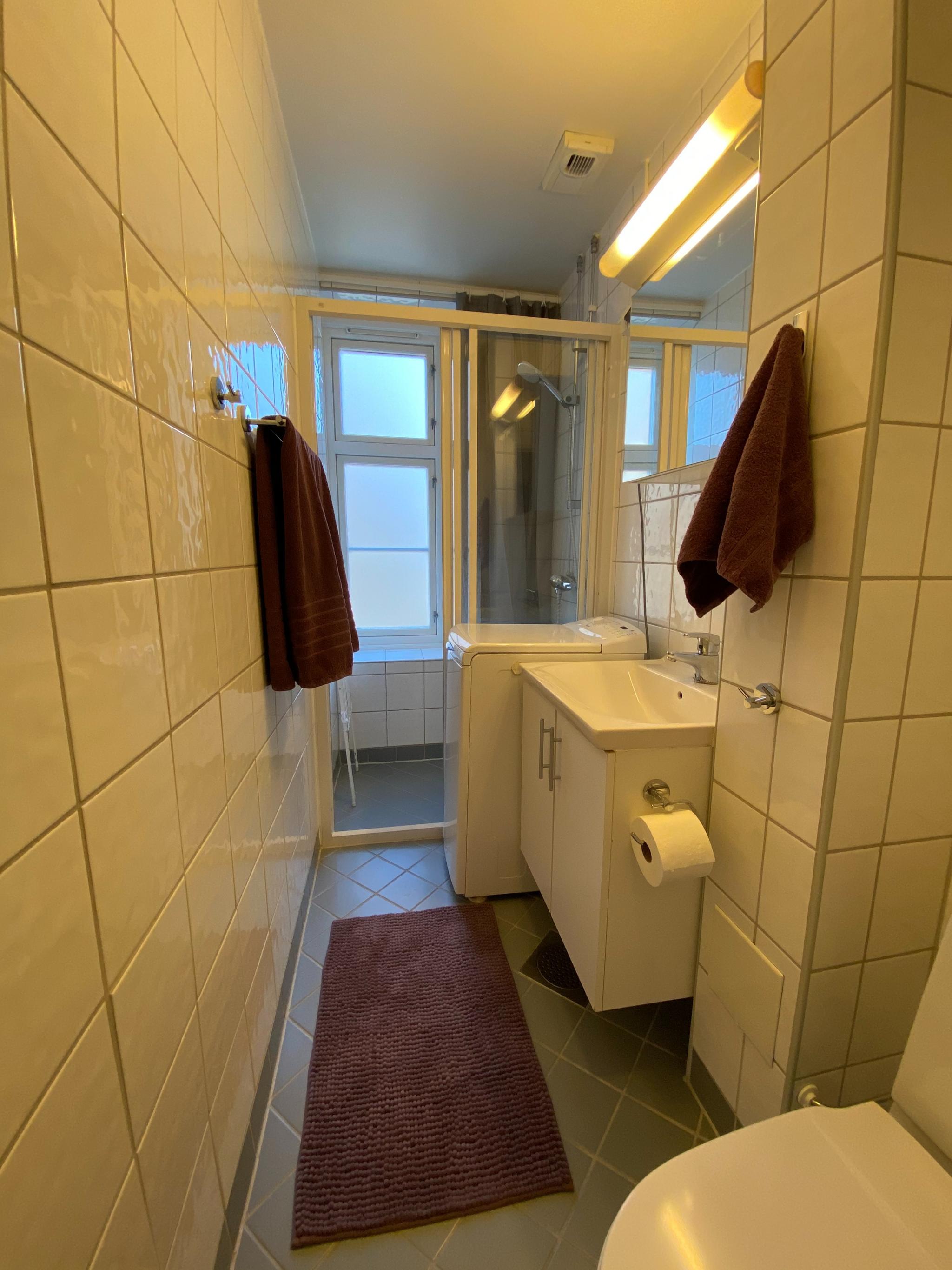 Baderom med varmekabler og vaskemaskin.