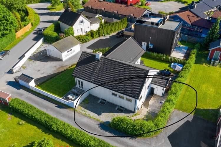 Leilighetens inngang, platting og biloppstillingsplass innenfor ringen. Merk at det har kommet opp nye hus rundt boligen etter at dette bildet ble tatt, men at disse har begrenset effekt for leieboligen på grunn av hekkens skjerming. 