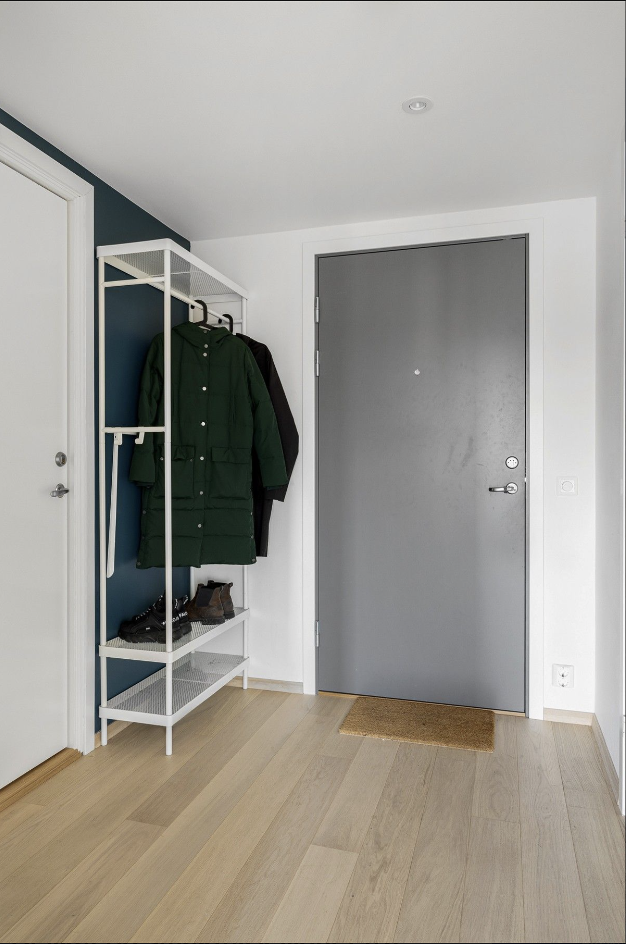 Hoveddør i grått og hybelens inngang til venstre.