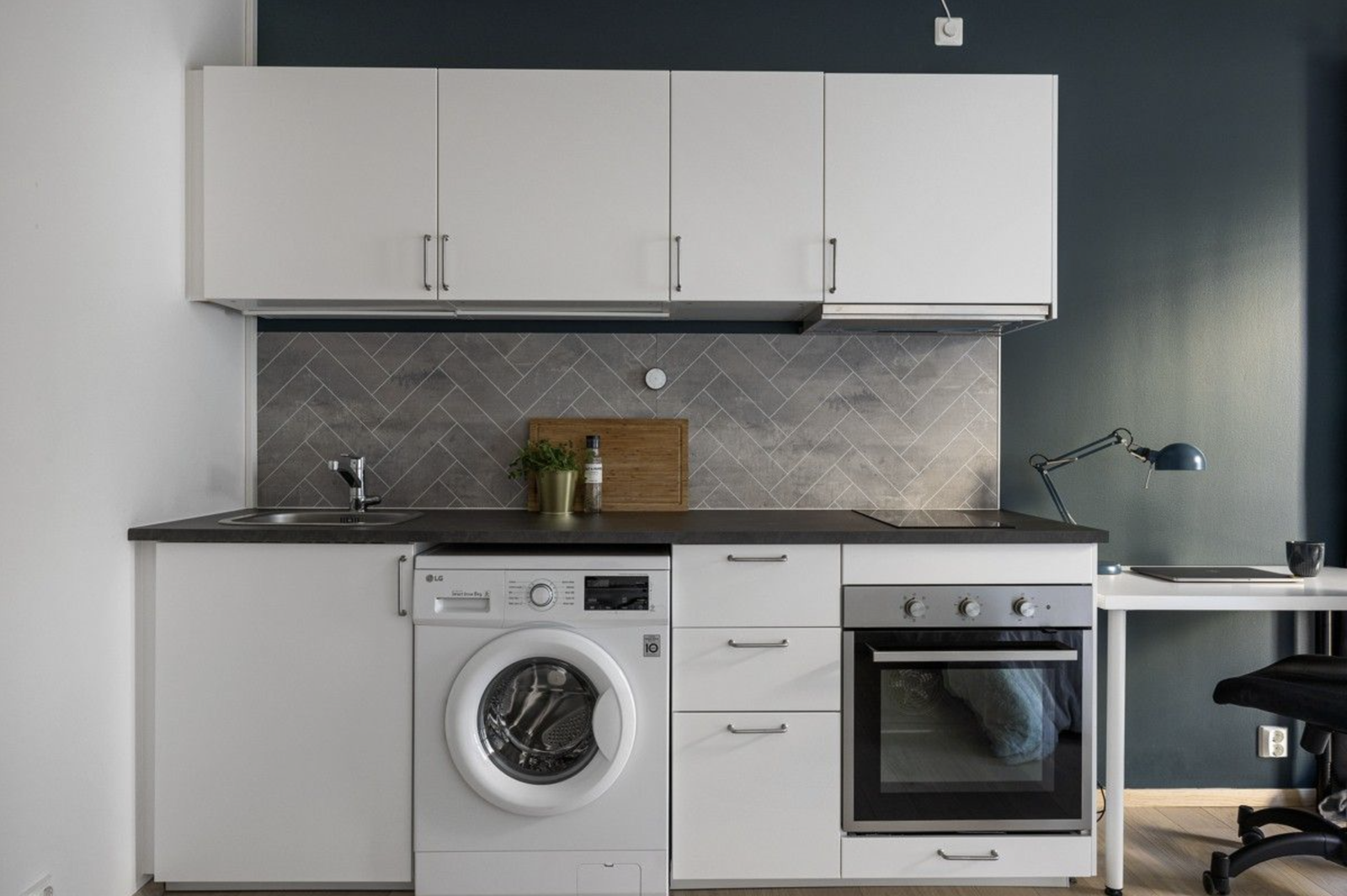 Kjøkken med ovn og koketopp, samt vaskemaskin.