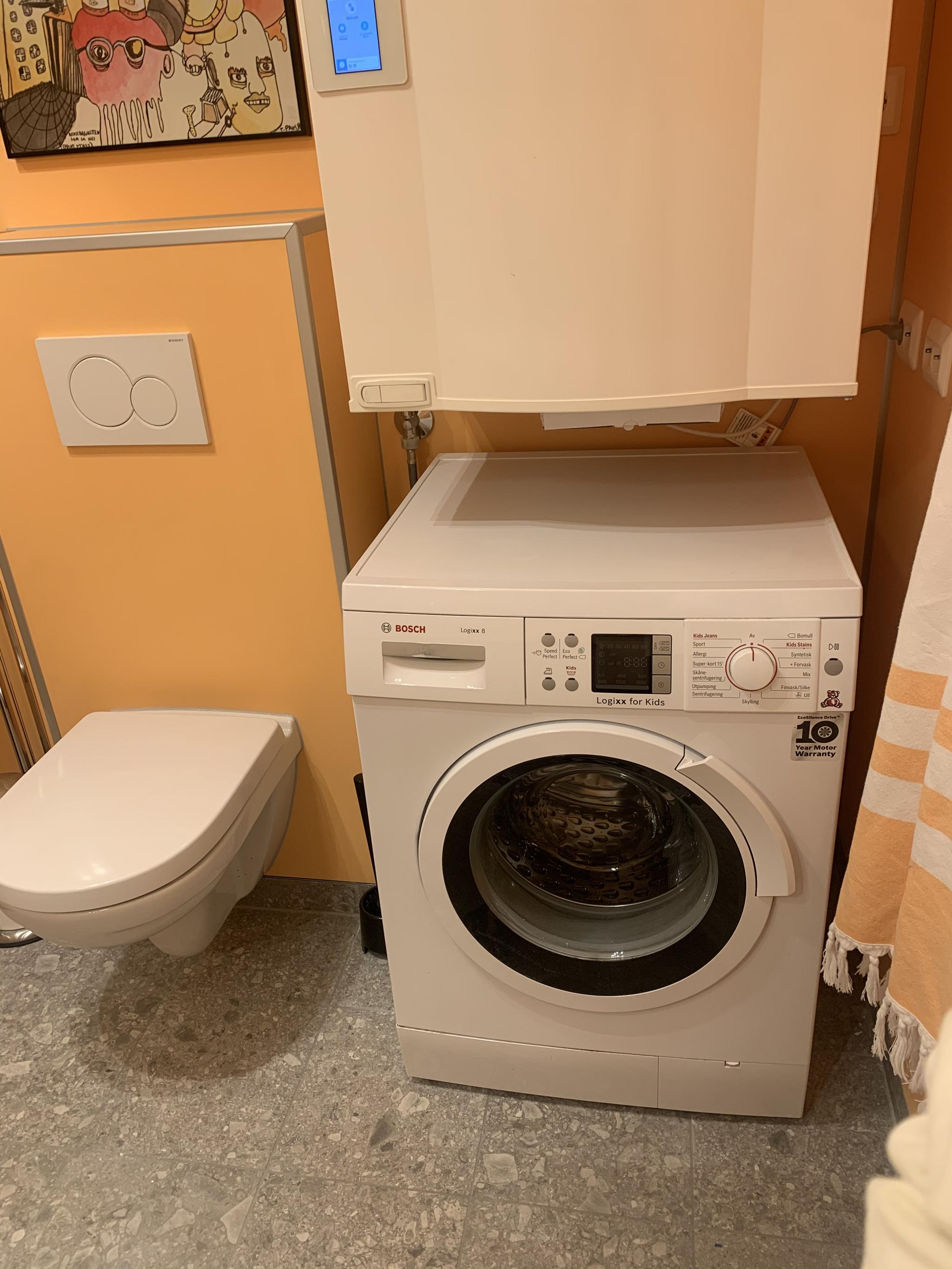 Vaskemaskin er installert. Skapet over vaskemaskinen er aggregat for balansert ventilasjon