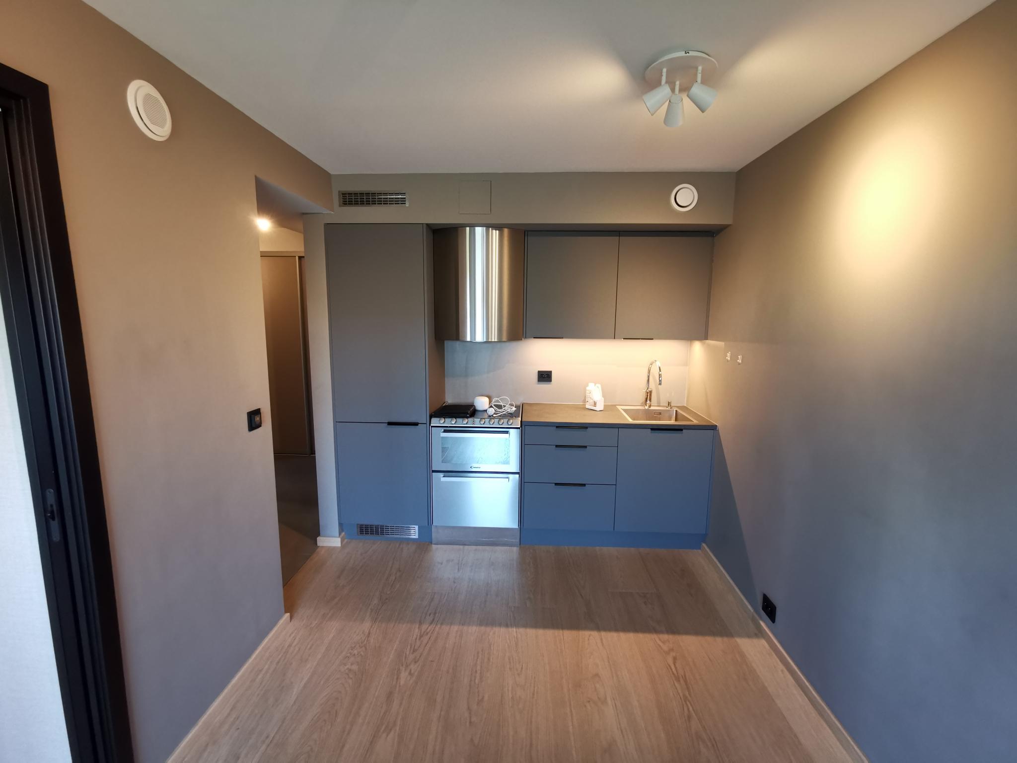 Kjøkken med kjøl/frys til venstre, komfyr med oppvaskmaskin, skuffeseksjon og uttrekkbar avfallssortering. Ventilator med kullfilter og 2 stk. overskap.