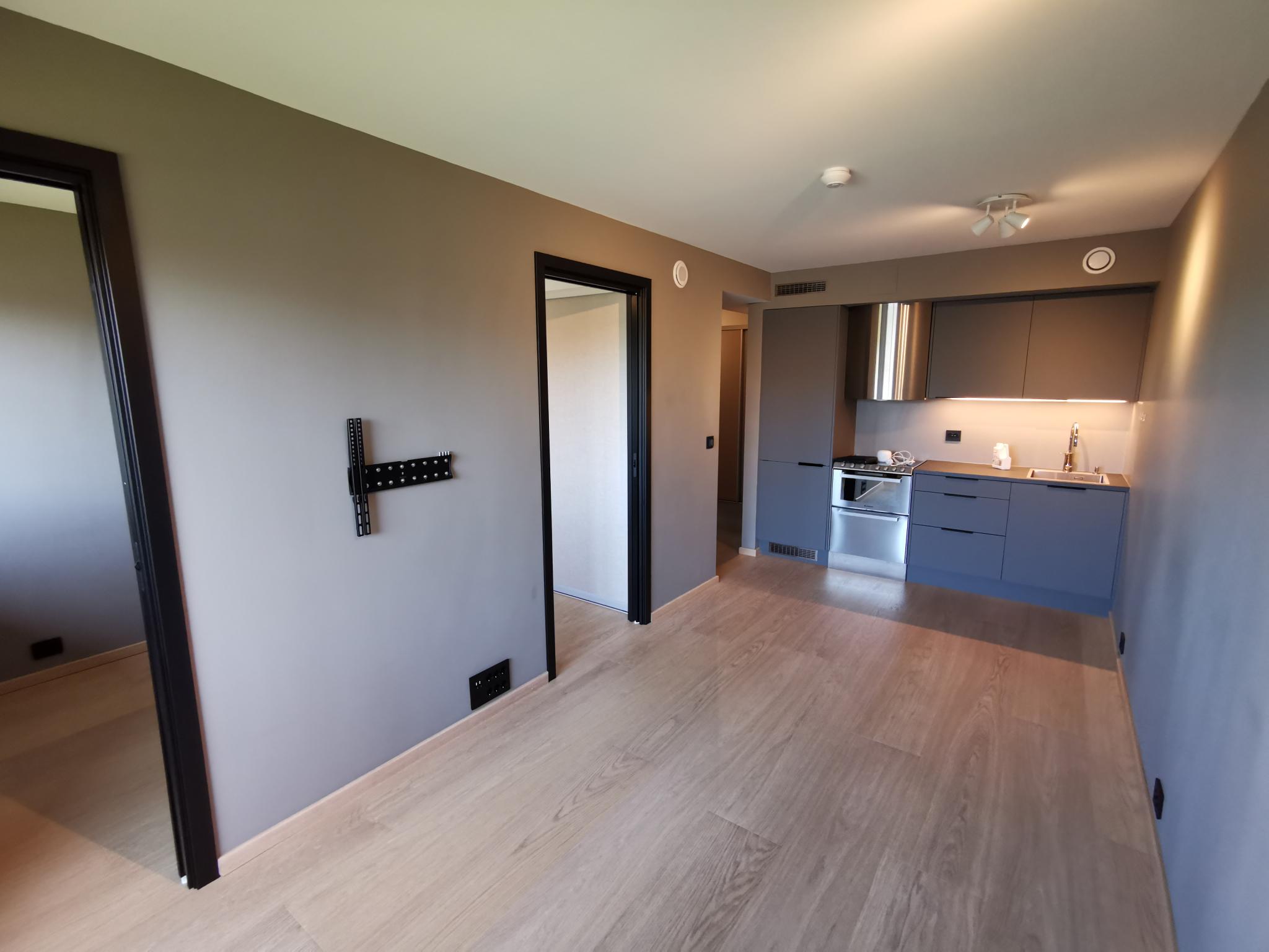 Stue sett mot kjøkken. Soverom og entre til venstre. God plass til spisebord i overgang mellom stue og kjøkken.