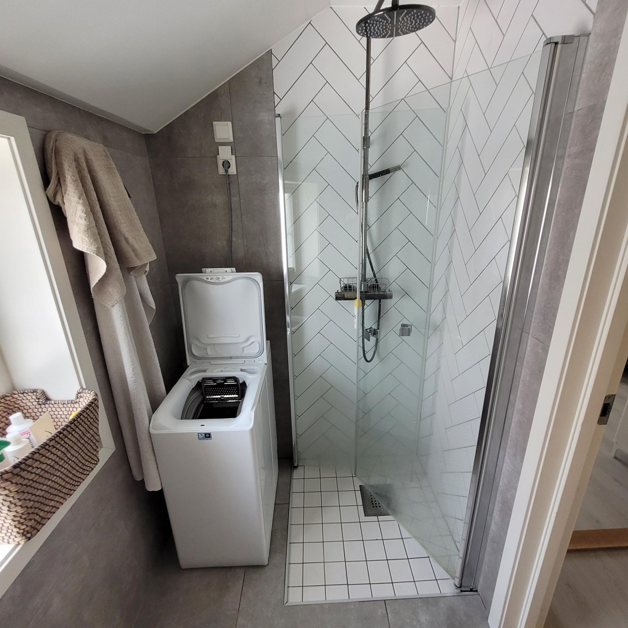 Bad har flislagt dusjavlukke og vaskemaskin