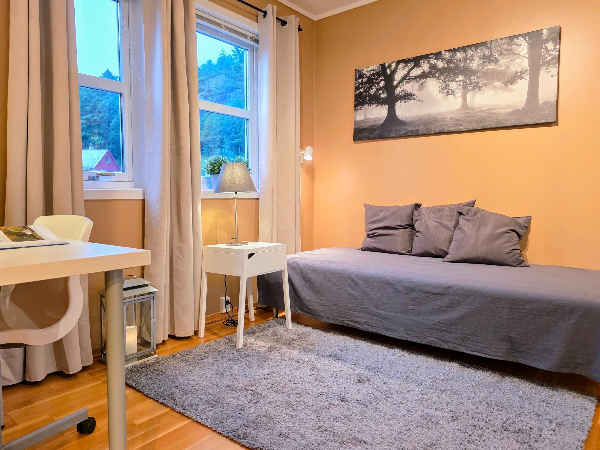 Flott soverom med seng, nattbord, og skrivebord.