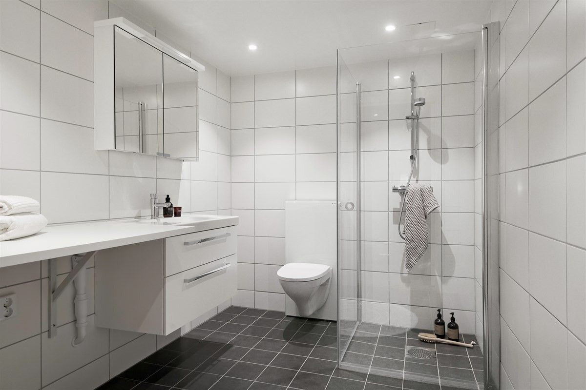 Badet har varme i gulv og tidløse fliser. Det er innfellbare dusjvegger med smussavstøtende glass