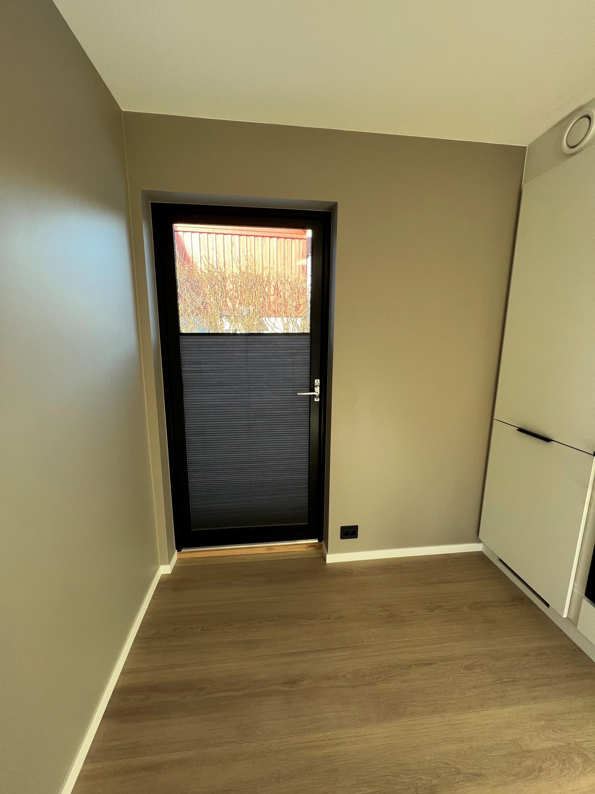 Inngang med plisséer på døren. Det er mulig å dra plisséene ovenfra ned og motsatt.