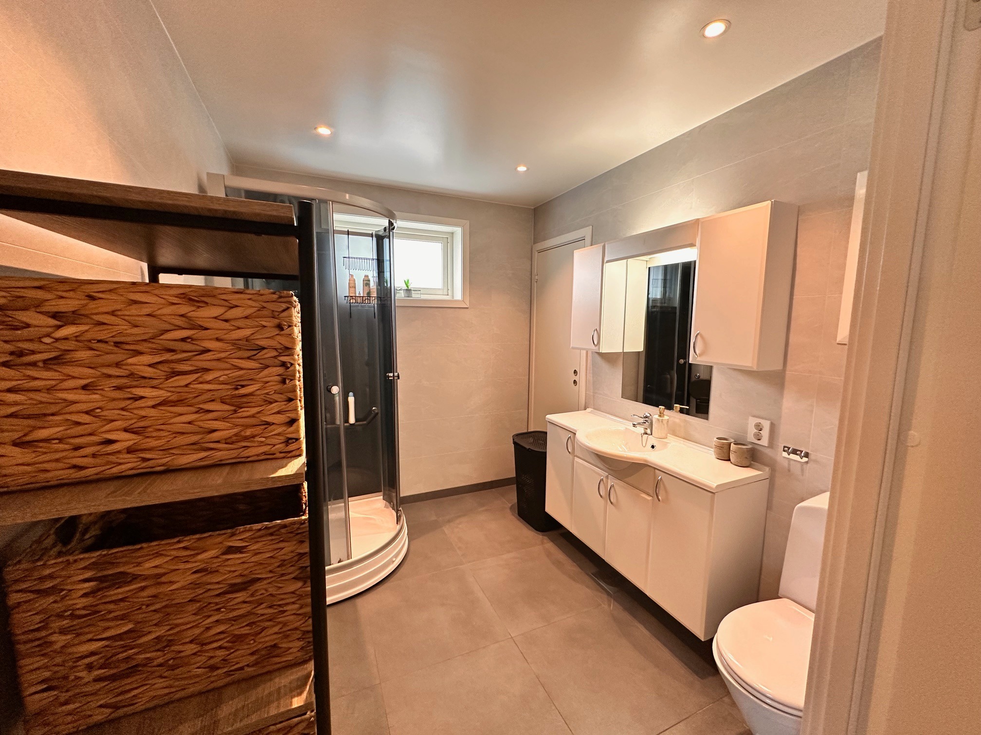 Bad med fliser på gulv, varmekabler, innredning, dusj, wc og spotter i tak