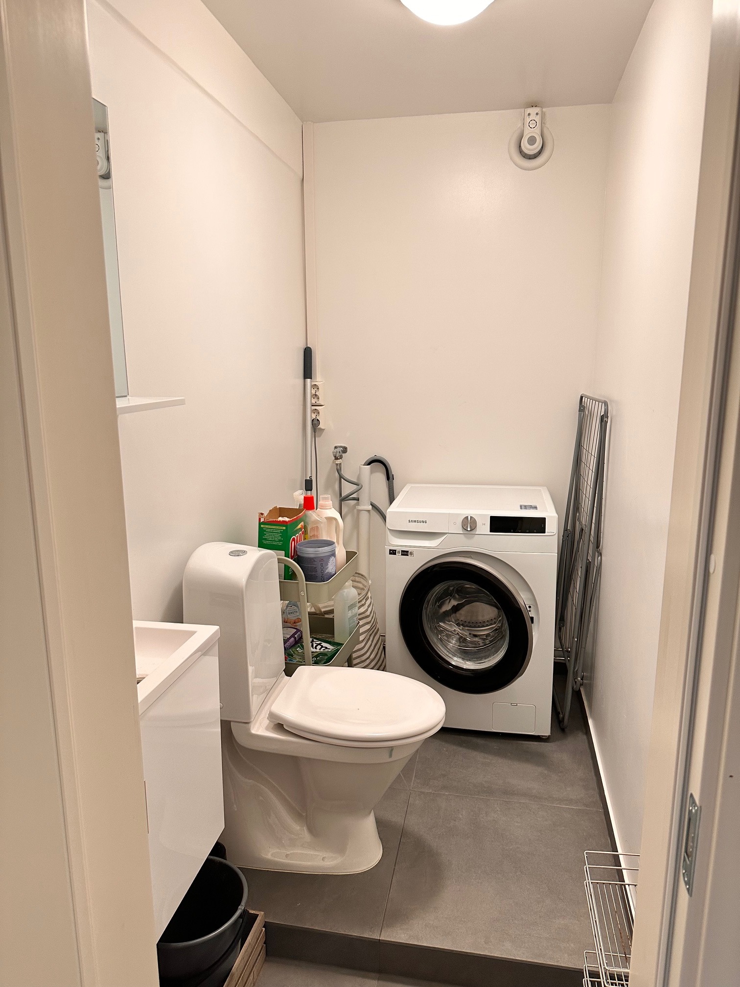 Vaskerom med fliser på gulv, wc, vask og plass for vaskemaskin og tørketrommel