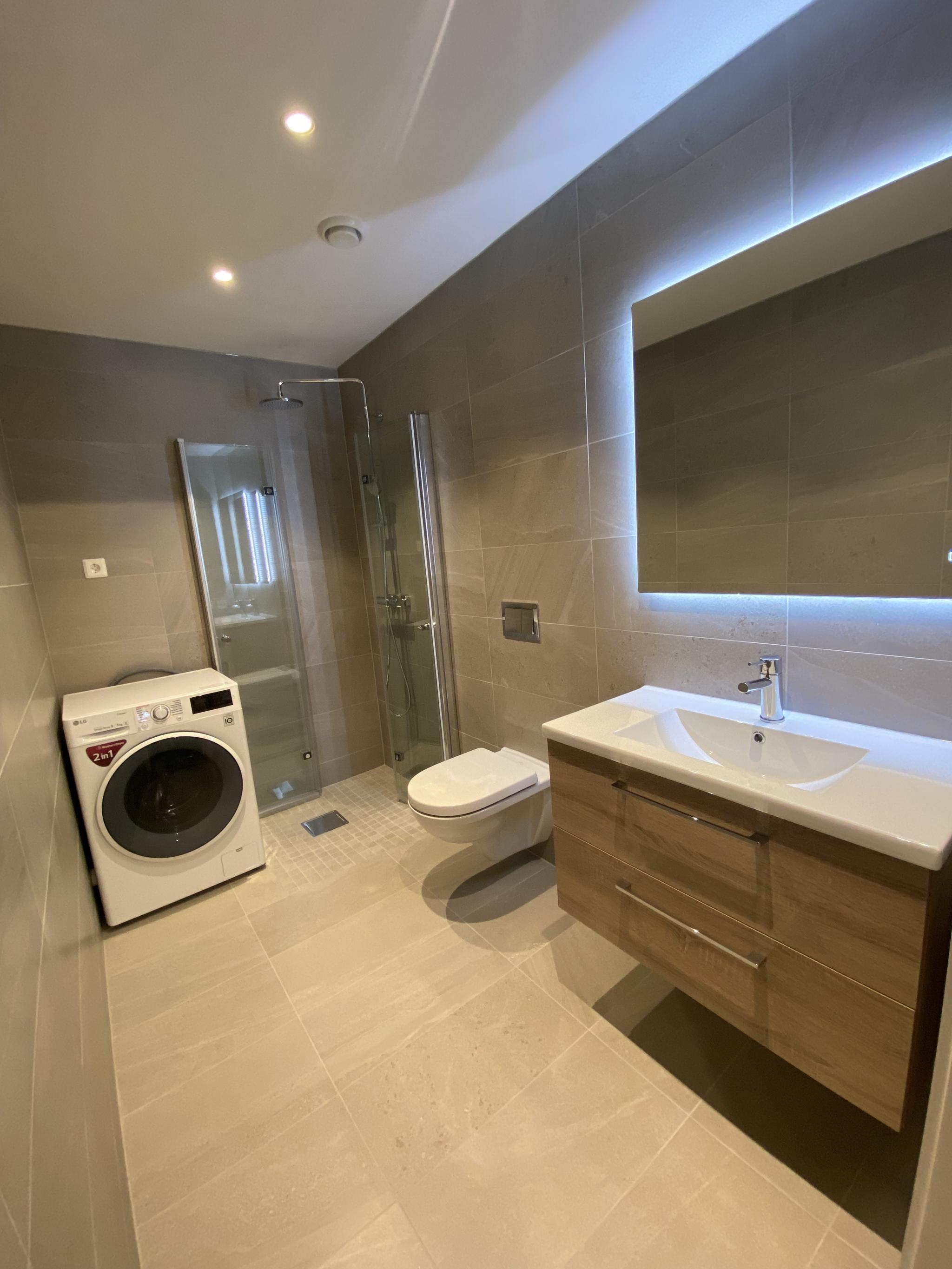 Meget pent bad med store fliser, spotter og kombinert vask/tørk