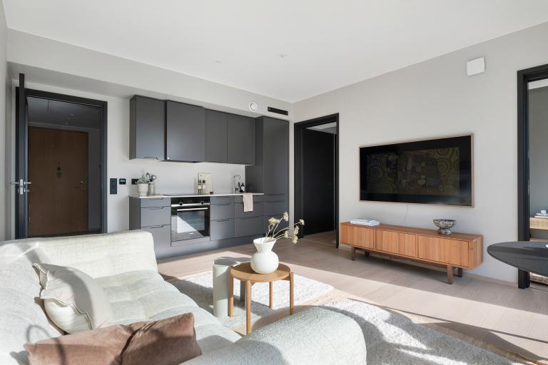 Gjennomført standard fra 2021 med god takhøyde og lekker 1-stavs parkett over vannbåren gulvvarme. Stilrent kjøkken fra HTH med slette fronter i koksgrå utførelse og benkeplate i stein.