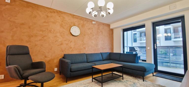 Romslig stue med store vindusflater og inngang til balkong