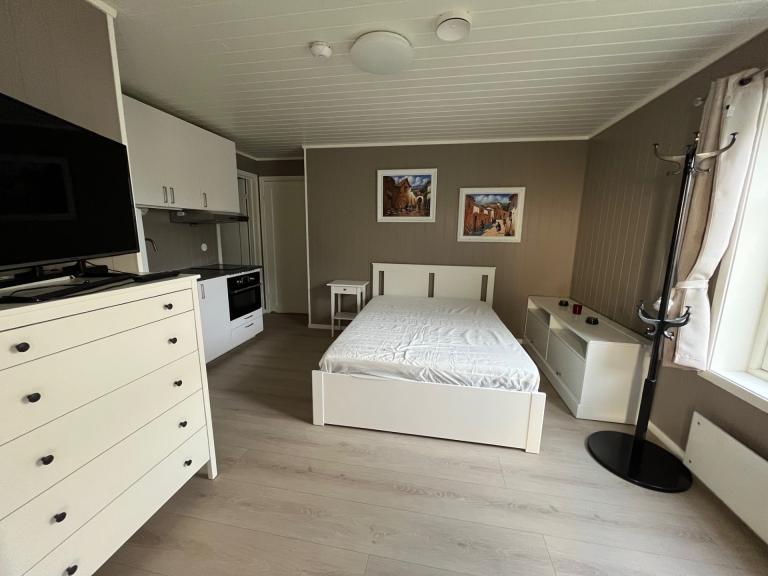 Romslig soverom utstyrt med en 140x200 cm seng, nattbord, kommoder, speil, gardiner, klesstativ, TV-hylle, garderobe og kommoder