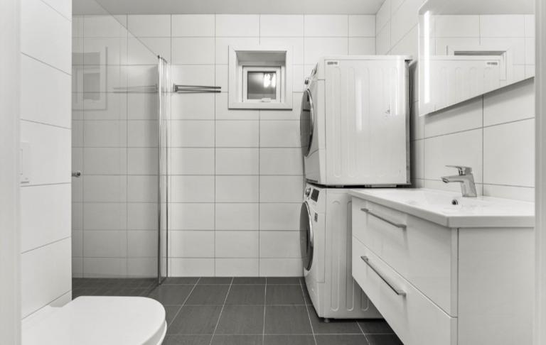 Bad med mørk gulvfliser og hvite veggfliser.